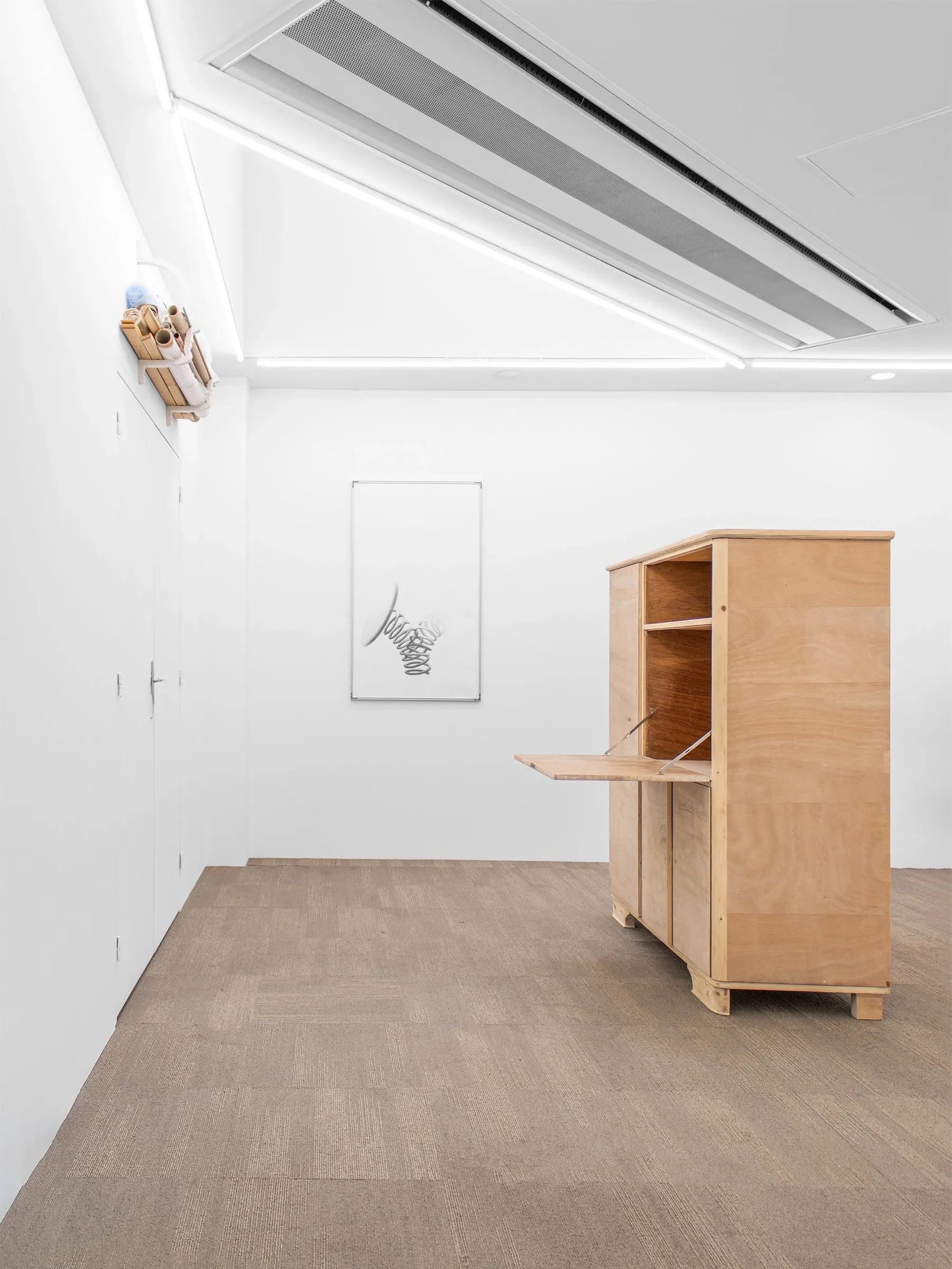 What We See, What Looks Back at Us at Emergency Space, Paris, 2026. Wide gallery view with a plywood cabinet, a graphite spring drawing and a wall-mounted paper rack. Photo: Misha Gudwin