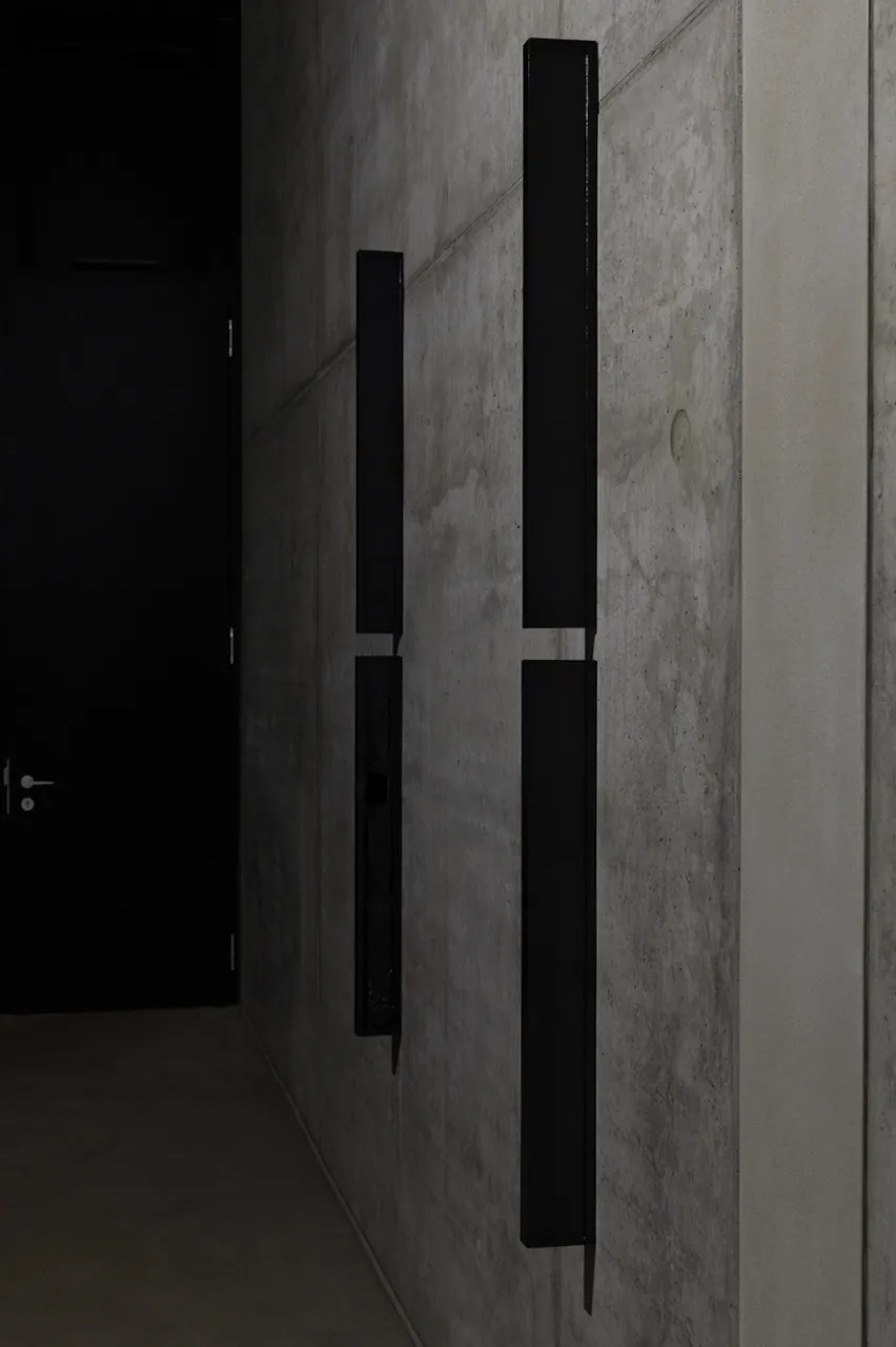 Exhibition review of Sofiia Yesakova: The Solemnity of the Repulsive at ROAM projects e.V., Berlin, 2026. Two tall black lacquered wood panels mounted vertically on a raw concrete wall.