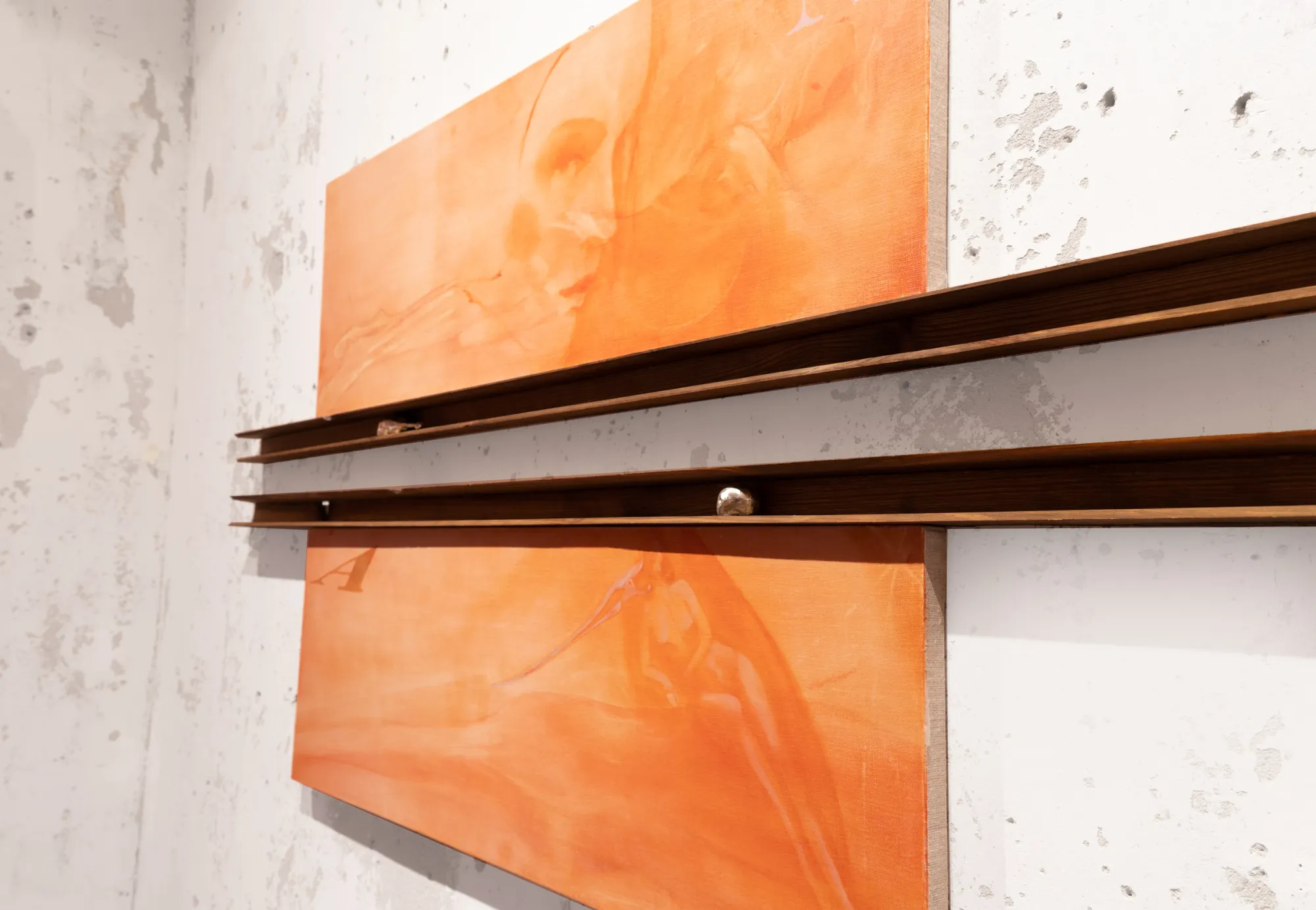 Exhibition review of Amelia Woroszyl: Silly! Devil! at Crum Heaven, Stockholm, 2026. Side angle of two orange panels and the dark wood rails holding a small charm.