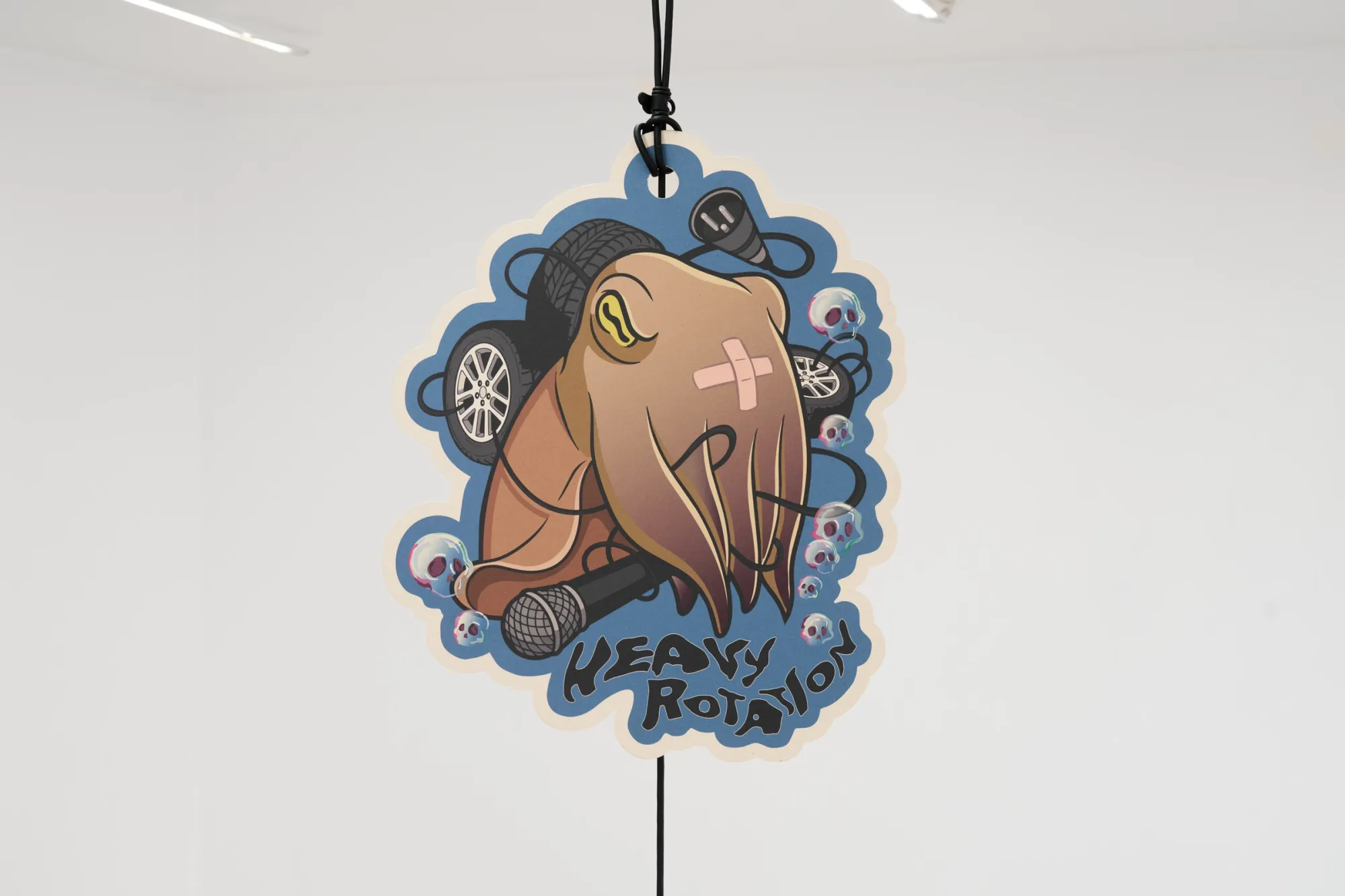 Exhibition review of Elisa Diaferia & Juri Simoncini: Sequence for an Optimal Dispatch at aaaa nordhavn, Copenhagen, 2026. Blue cut-out print of a squid over microphones and tyres, lettered Heavy Rotation.