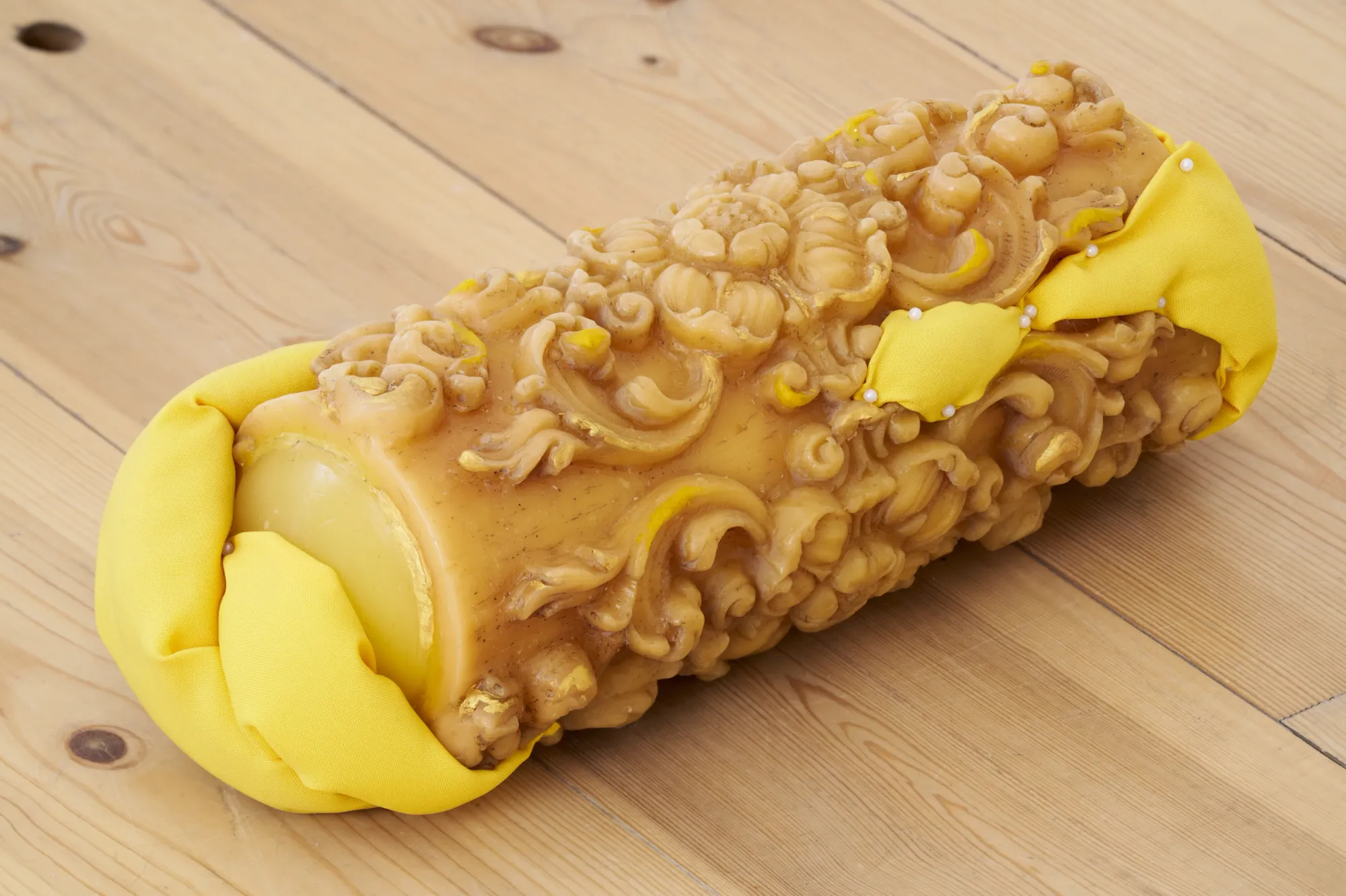 Exhibition review of Elisa Diaferia & Juri Simoncini: Sequence for an Optimal Dispatch at aaaa nordhavn, Copenhagen, 2026. Ornate beeswax roll wrapped in yellow padding on a pine floor.