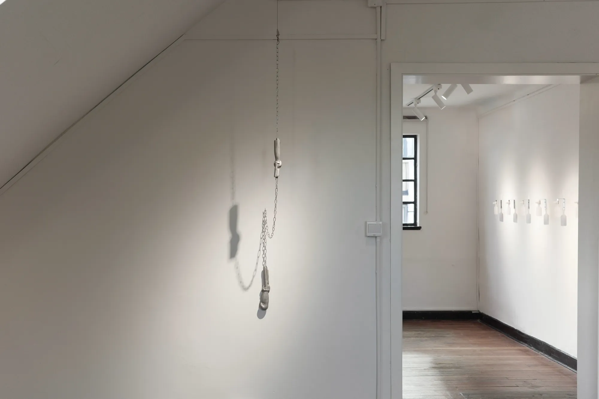Exhibition review of Eva Chenyao He: Procrustean at COLLECTA, Shanghai, 2026. A resin joint form hangs from a chain near a doorway.