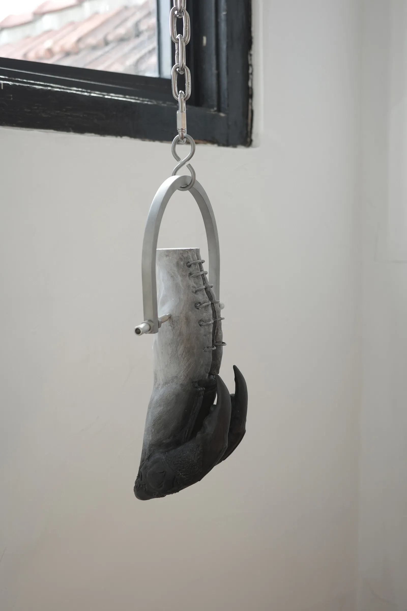 catapult contemporary Exhibition review of Eva Chenyao He: Procrustean at COLLECTA, Shanghai, 2026. A pale claw-like limb hangs by a chain before a window.