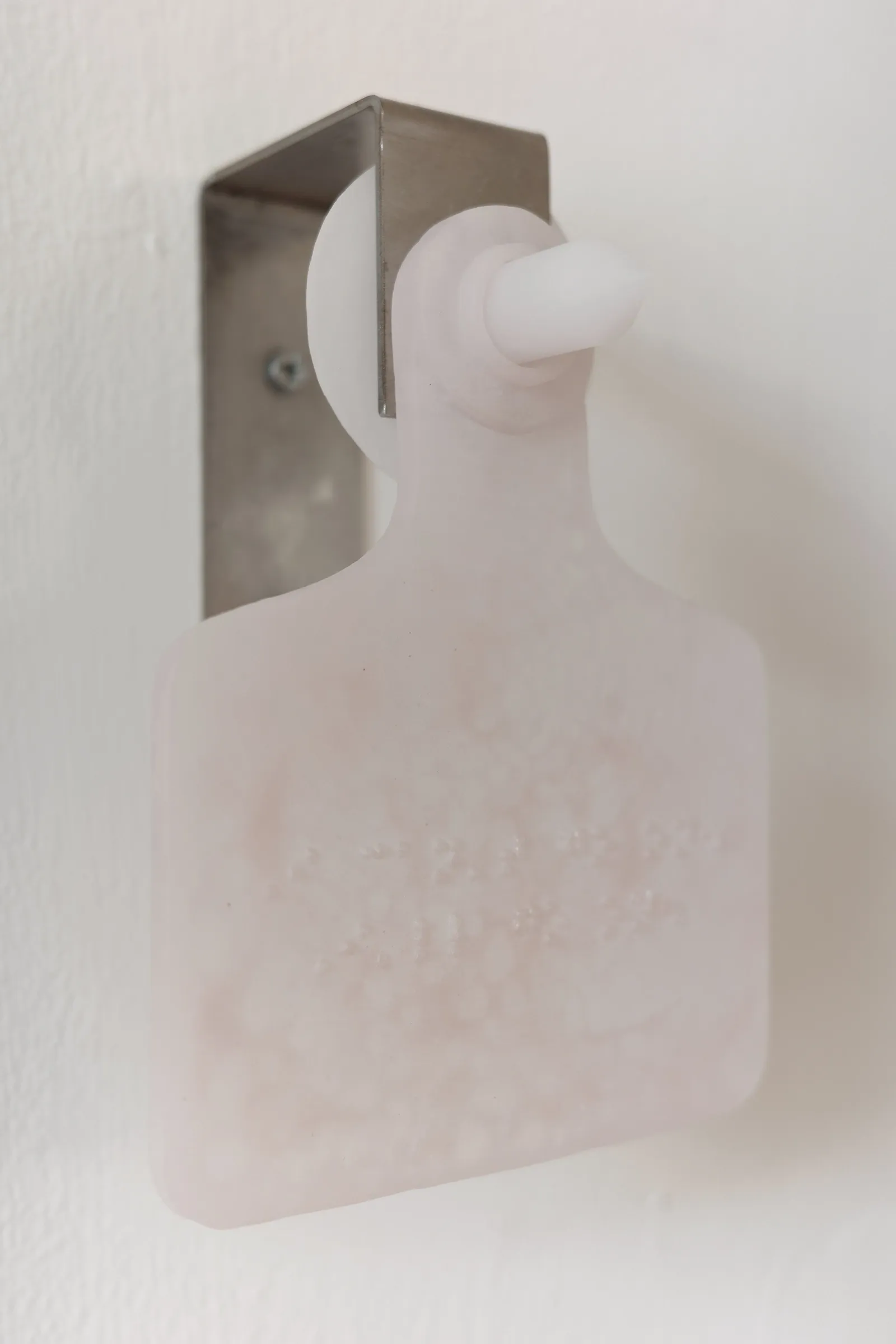 Exhibition review of Eva Chenyao He: Procrustean at COLLECTA, Shanghai, 2026. Six pale pate de verre ear tags mounted in a row on a wall.