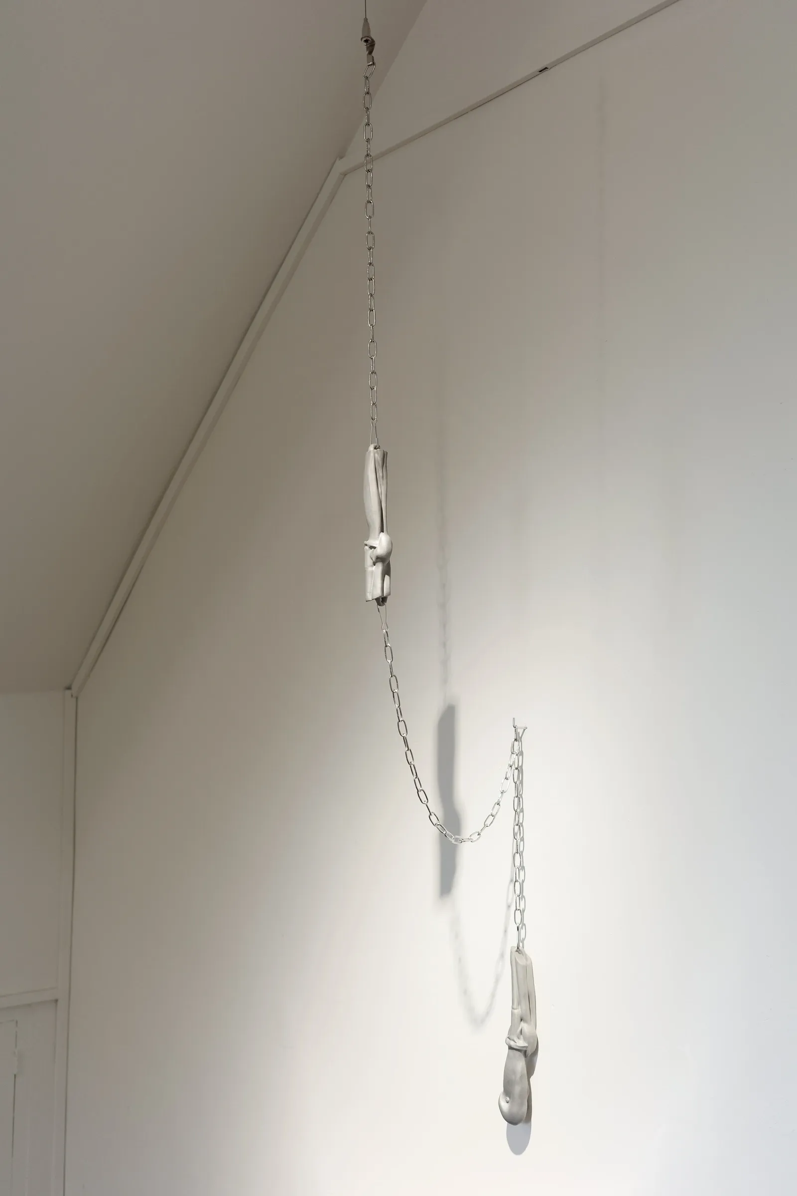 Exhibition review of Eva Chenyao He: Procrustean at COLLECTA, Shanghai, 2026. Two resin joint forms hang at different heights from a chain.