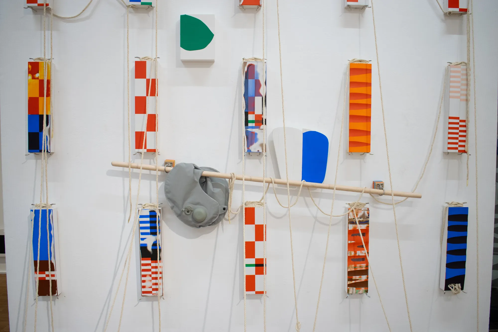 Artist Profile Feature: Hendrick Dialer, dozens of small painted panels on ropes hanging against a white wall, Parallel Vienna 2026.