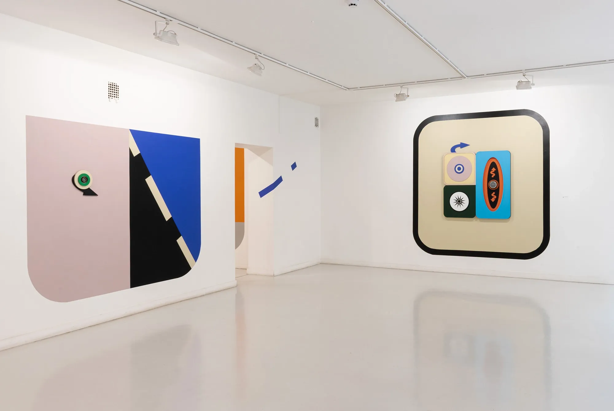 Exhibition review of Kaija Hinkula: You Are Here at Ama Gallery, Helsinki, 2026. A pink and blue shield-shaped wood relief beside an orange-bordered square painting.