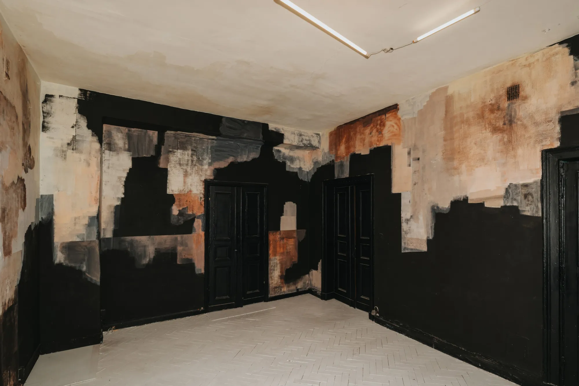 Exhibition review of Paulina Semkowicz: Residency: The Wall at Galeria S35, Łódź, 2026. Corner with two black doors, grey, rust and peach patches spreading from the ceiling line over black.