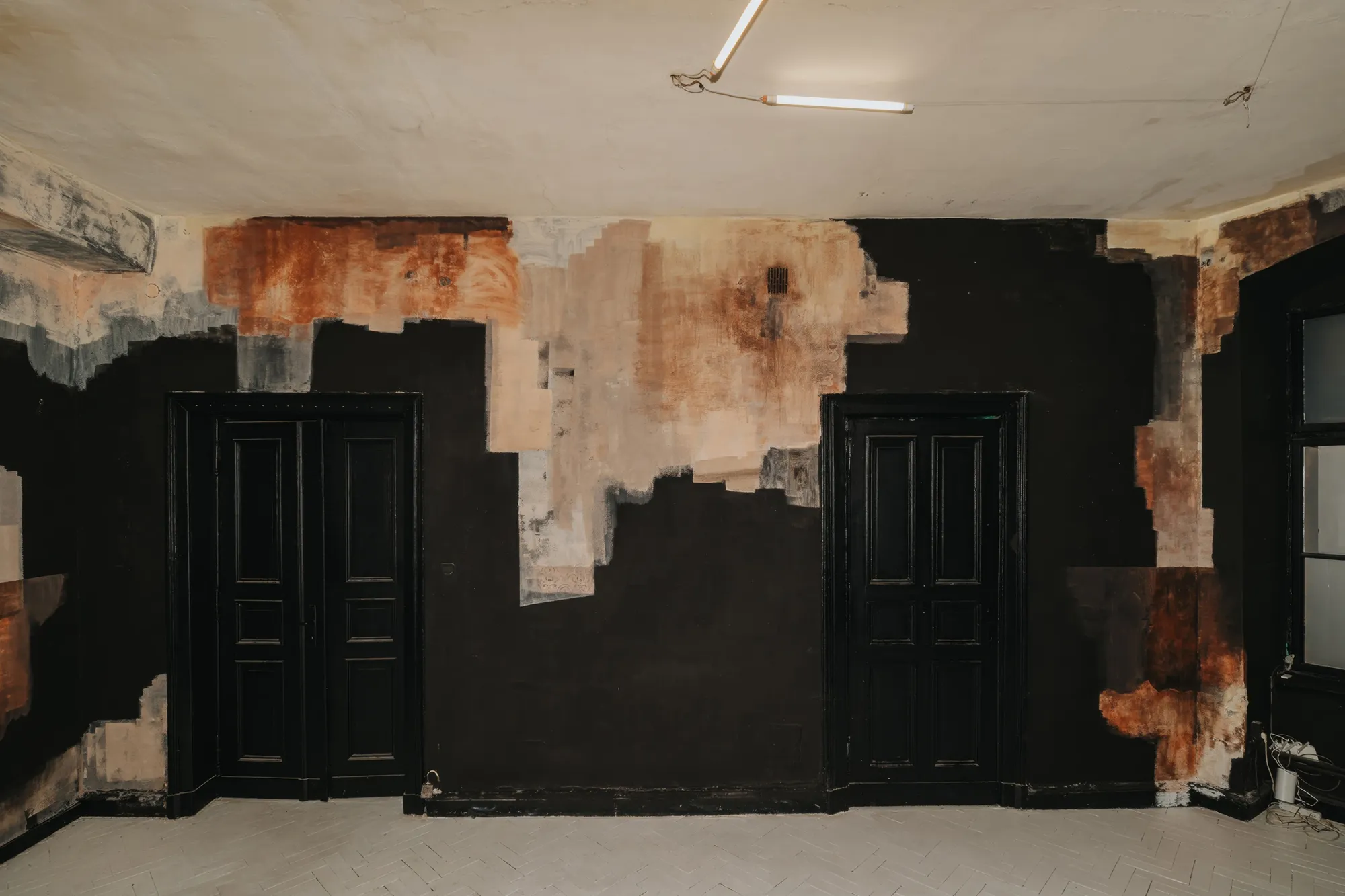 Exhibition review of Paulina Semkowicz: Residency: The Wall at Galeria S35, Łódź, 2026. Frontal wall with two black double doors under a band of rust, peach and grey pigment at ceiling height.