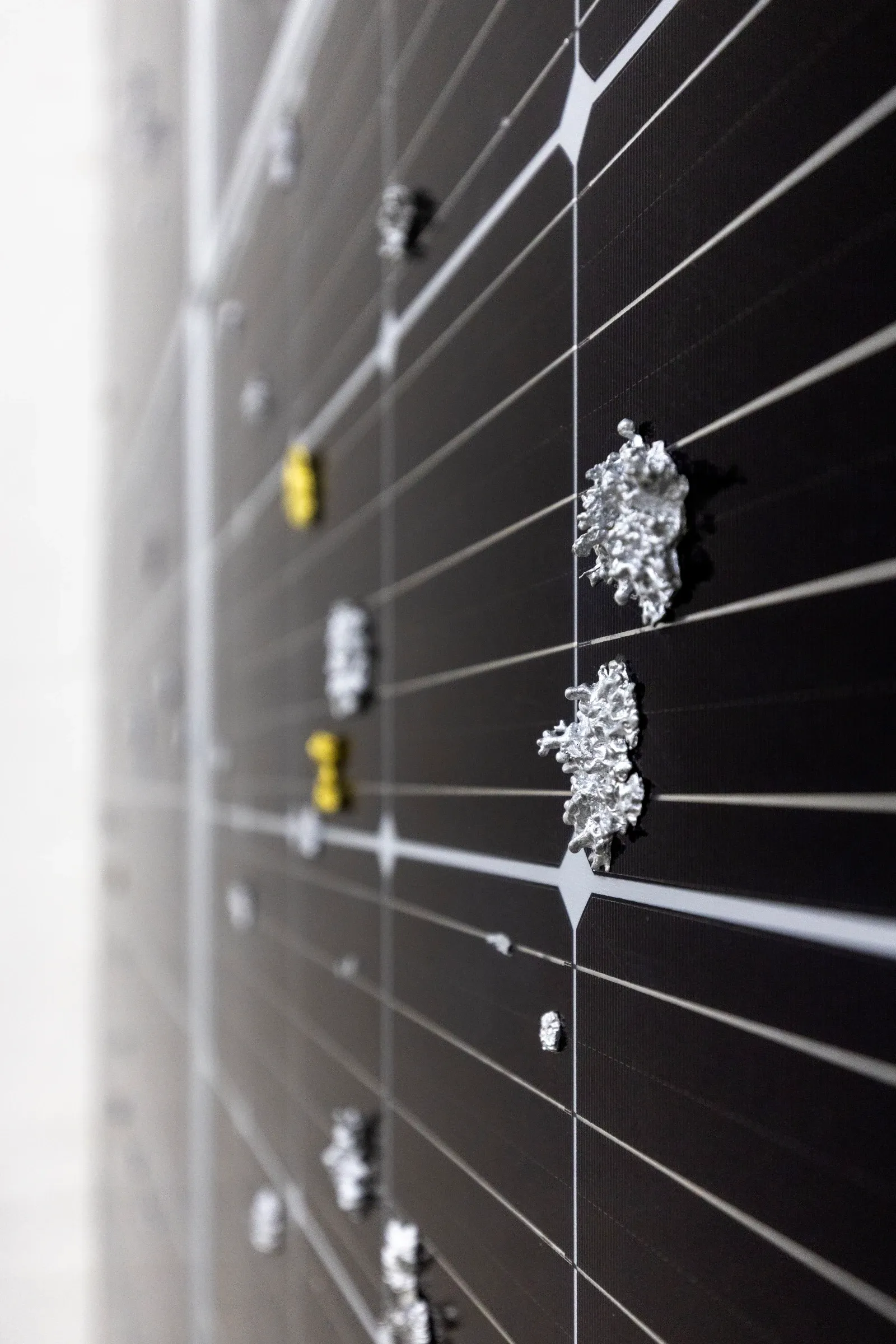 Exhibition review of Sari Palosaari: Substrate at Forum Box, Helsinki, 2026. Angled close-up of a solar panel with textured silver and yellow lichen casts protruding from the glass.