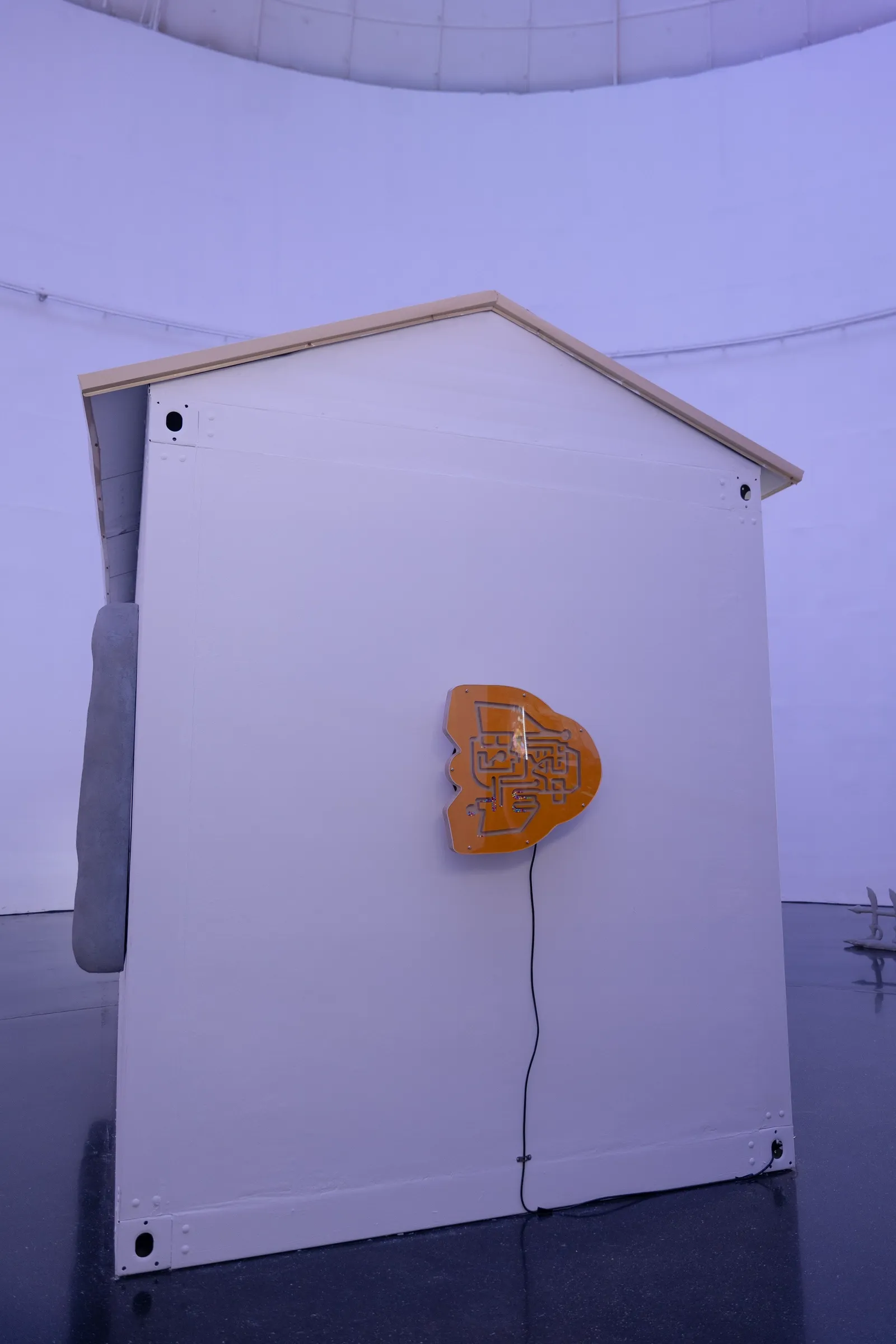 Exhibition review of Zhang Ting: TechDiumMory at TANK Shanghai, Shanghai, 2026. Orange acrylic maze panel with a cable, mounted on the white gable wall of the house.