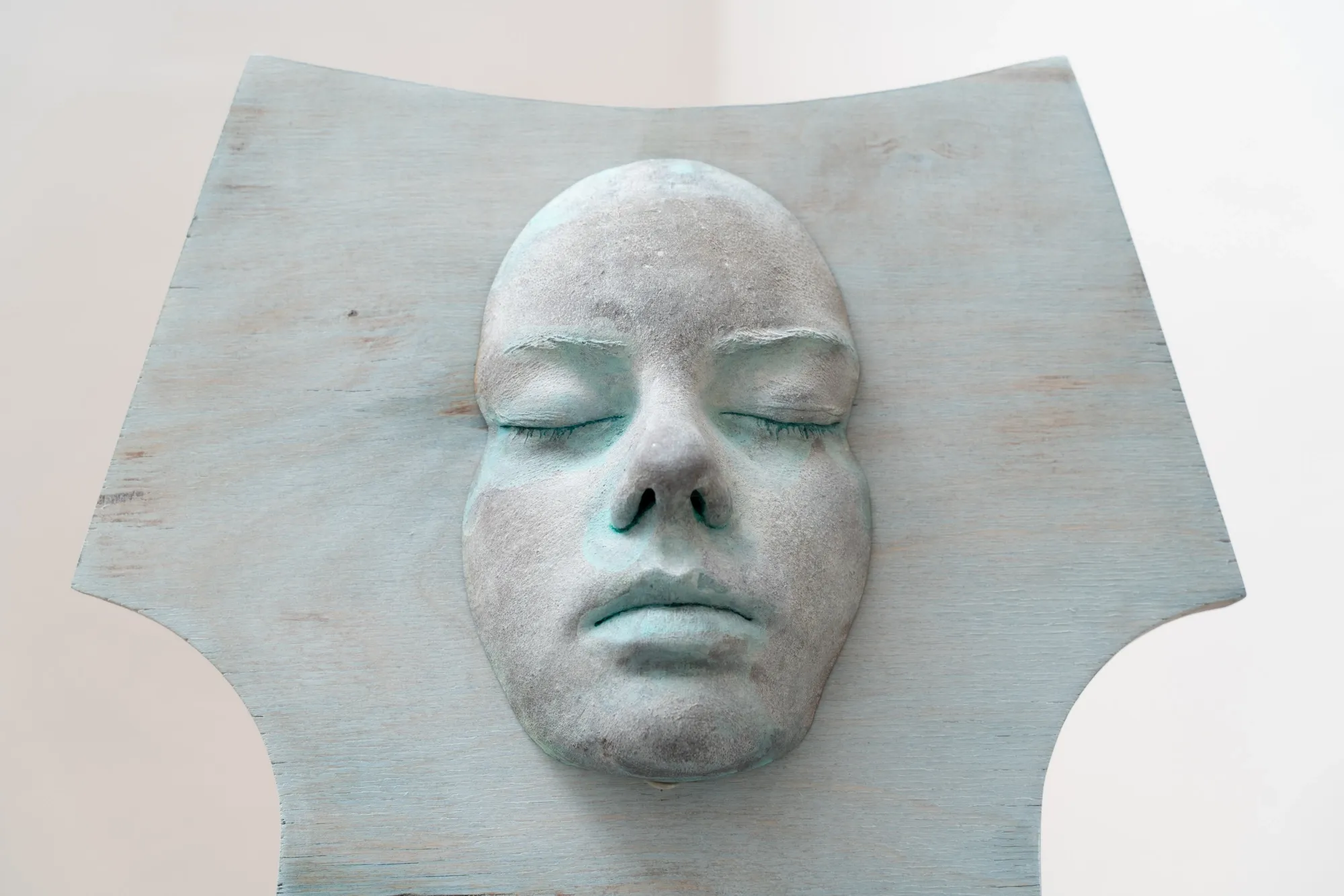 Ała Wierzbicka, MISE EN, Warsaw: close-up of a cast face with closed eyes set into a pale blue plywood chair back.