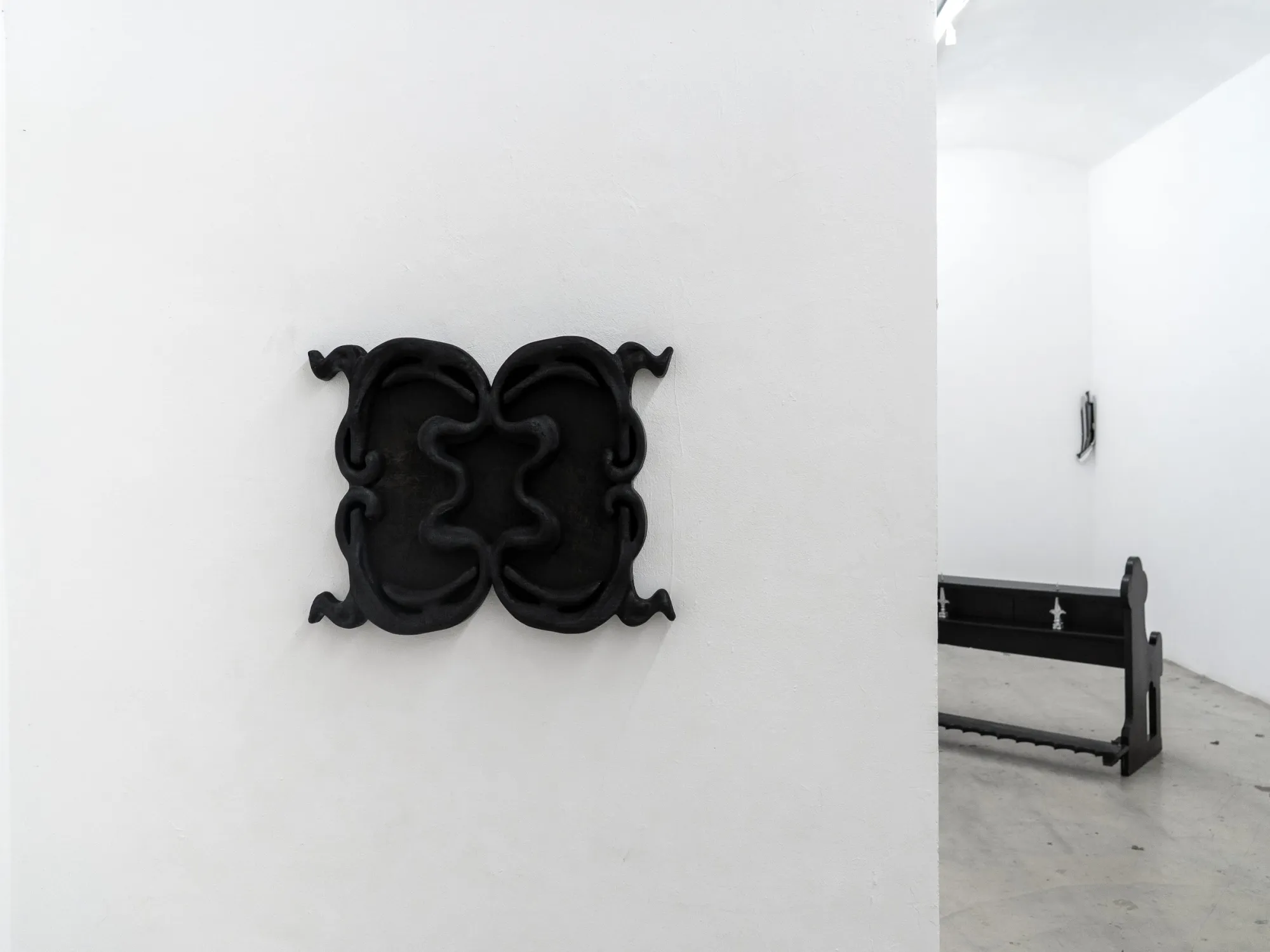 Exhibition review of AUSGEWEIDET / GUTTED at WAF Galerie, Vienna, 2026. Symmetrical black charred wood relief on a white wall. catapult contemporary review