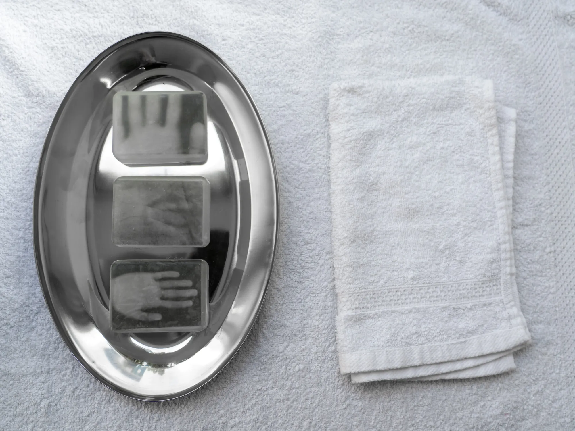 Exhibition review of AUSGEWEIDET / GUTTED at WAF Galerie, Vienna, 2026. Three glycerin soaps with hand images on a metal tray beside a white towel.
