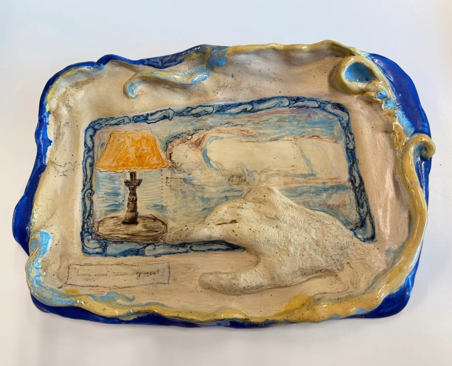 Christina Arark: ceramic tray with a wavy cobalt blue rim and a framed scene with an orange table lamp.