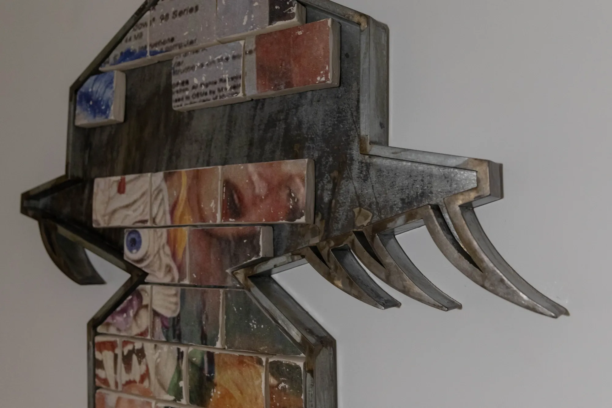 Fangyang, E.SCAPE art space, Shanghai: detail of a hat-shaped steel frame with curved claw forms and clay tiles showing an eye and printed text.