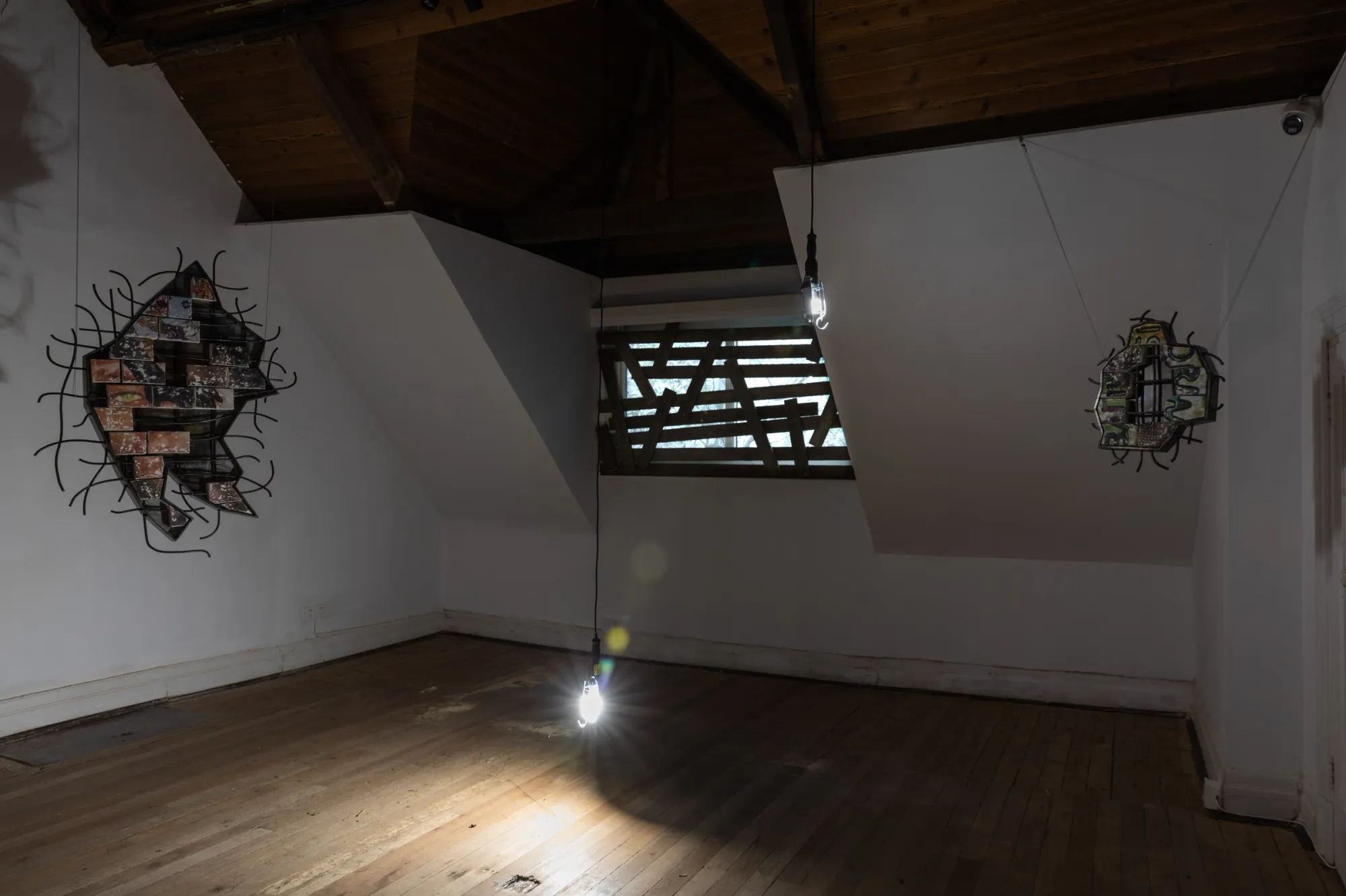 Fangyang, E.SCAPE art space, Shanghai: two clay and steel works with rebar hang in an attic room under a bare bulb.