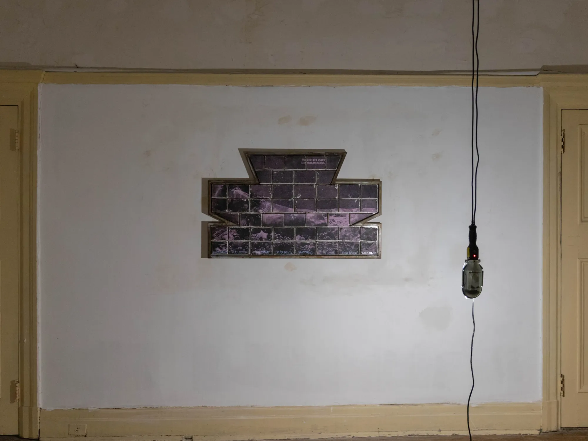 Fangyang, E.SCAPE art space, Shanghai: purple-toned brick-tile panel in a stepped steel frame on a white wall beside a hanging bulb.