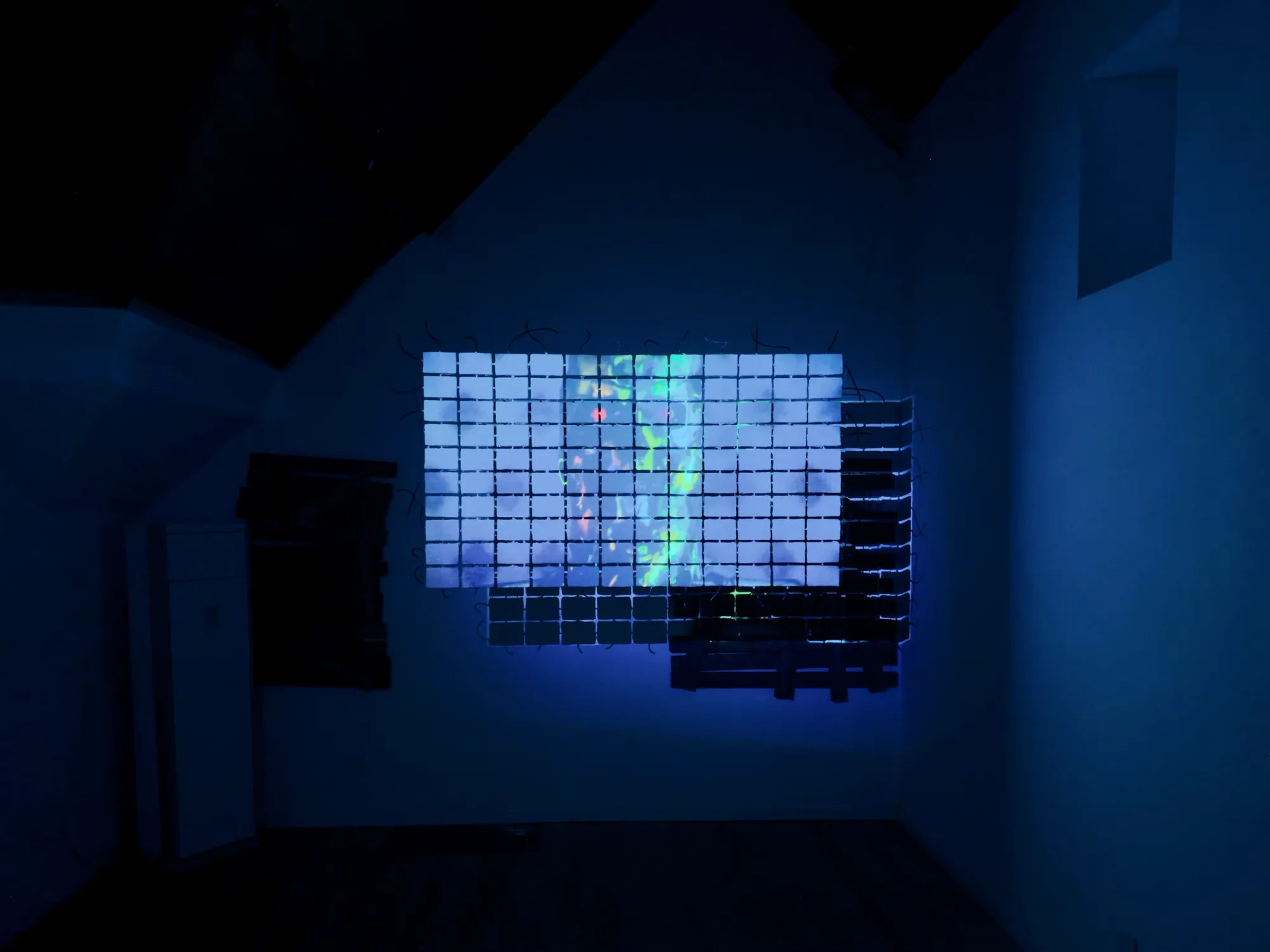 Fangyang, E.SCAPE art space, Shanghai: video projected onto a grid of suspended clay blocks in a dark attic room lit blue