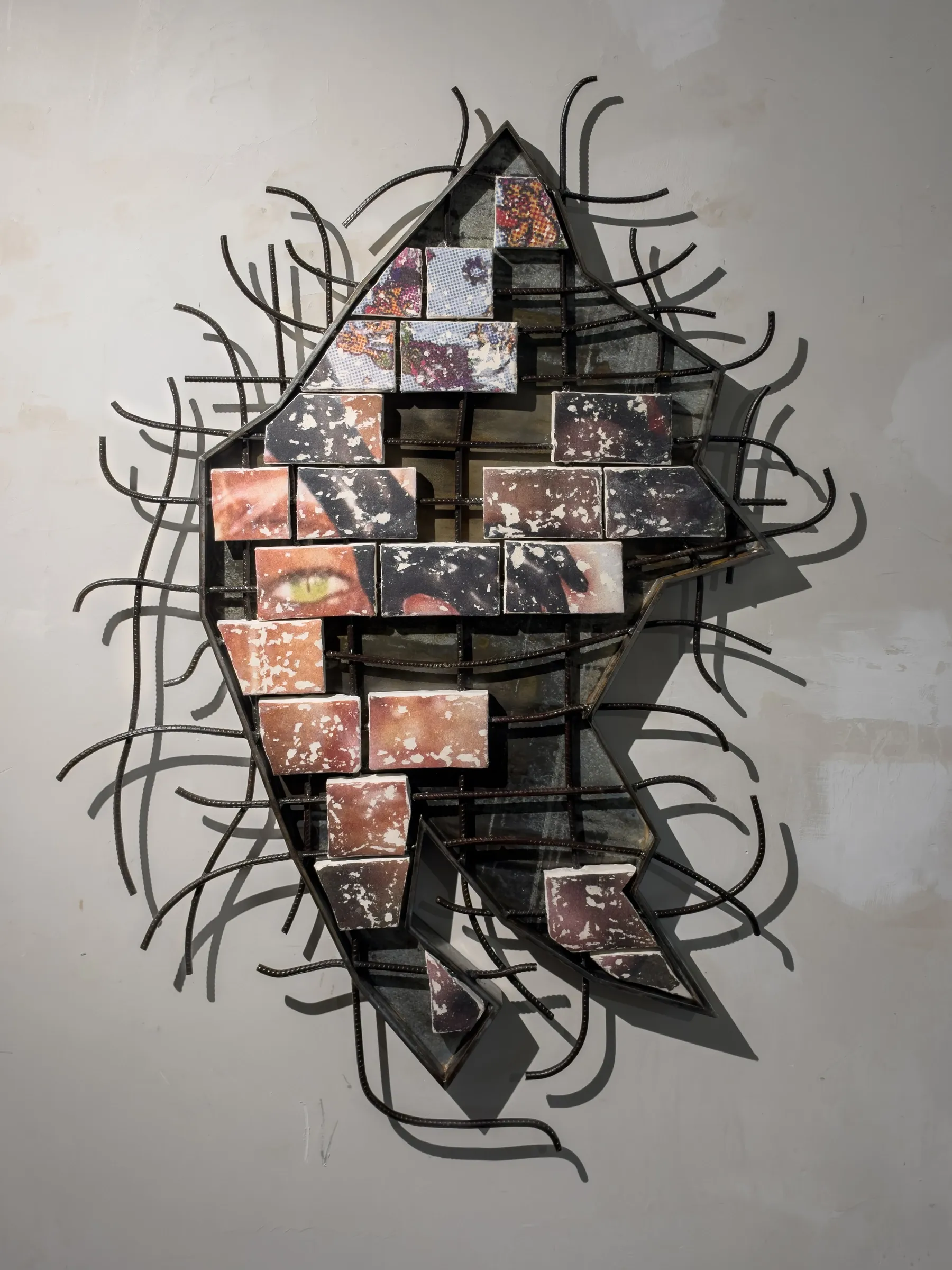 Fangyang, E.SCAPE art space, Shanghai: diamond-shaped steel frame holding brick-like clay tiles with a green eye, wrapped in curved black rebar.