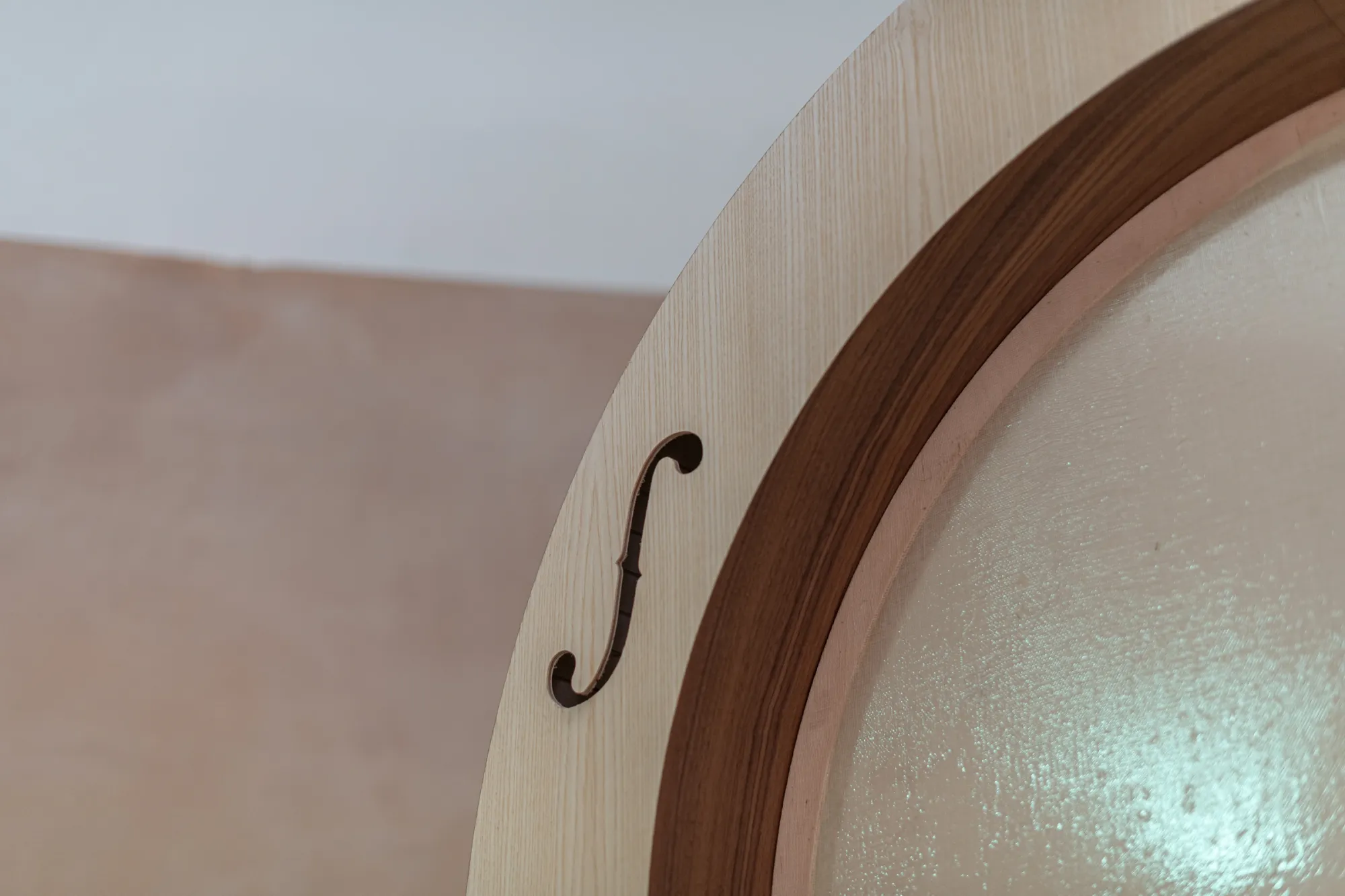Detail of Finbar Prior's Tympanum at OUTPOST Gallery, Norwich, 2026, showing the curved wooden frame, an f-shaped cut-out and textured membrane.