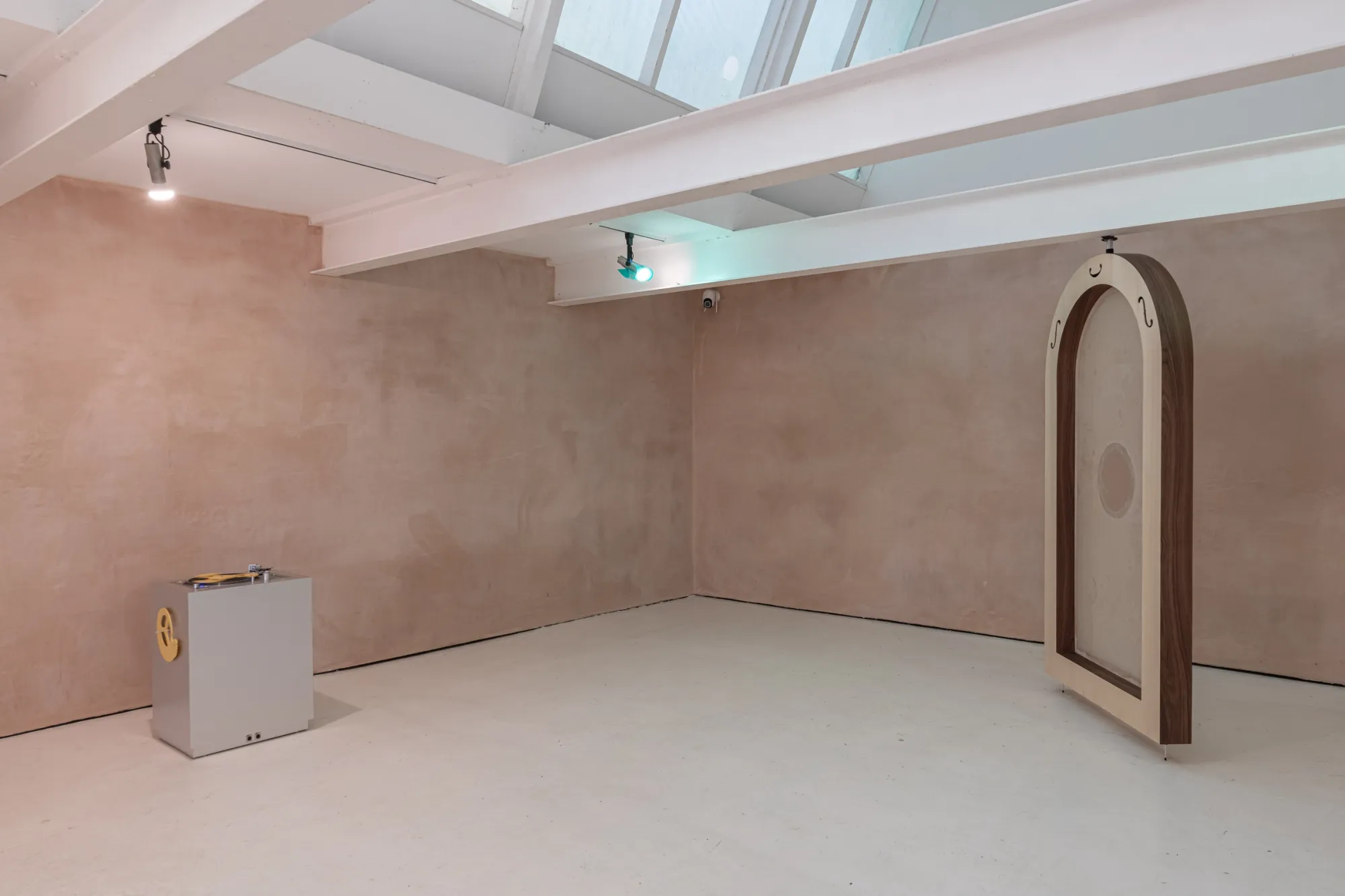 Installation view of Finbar Prior's Tympanums at OUTPOST Gallery, Norwich, 2026, with a wooden arch and a turntable on a grey plinth.