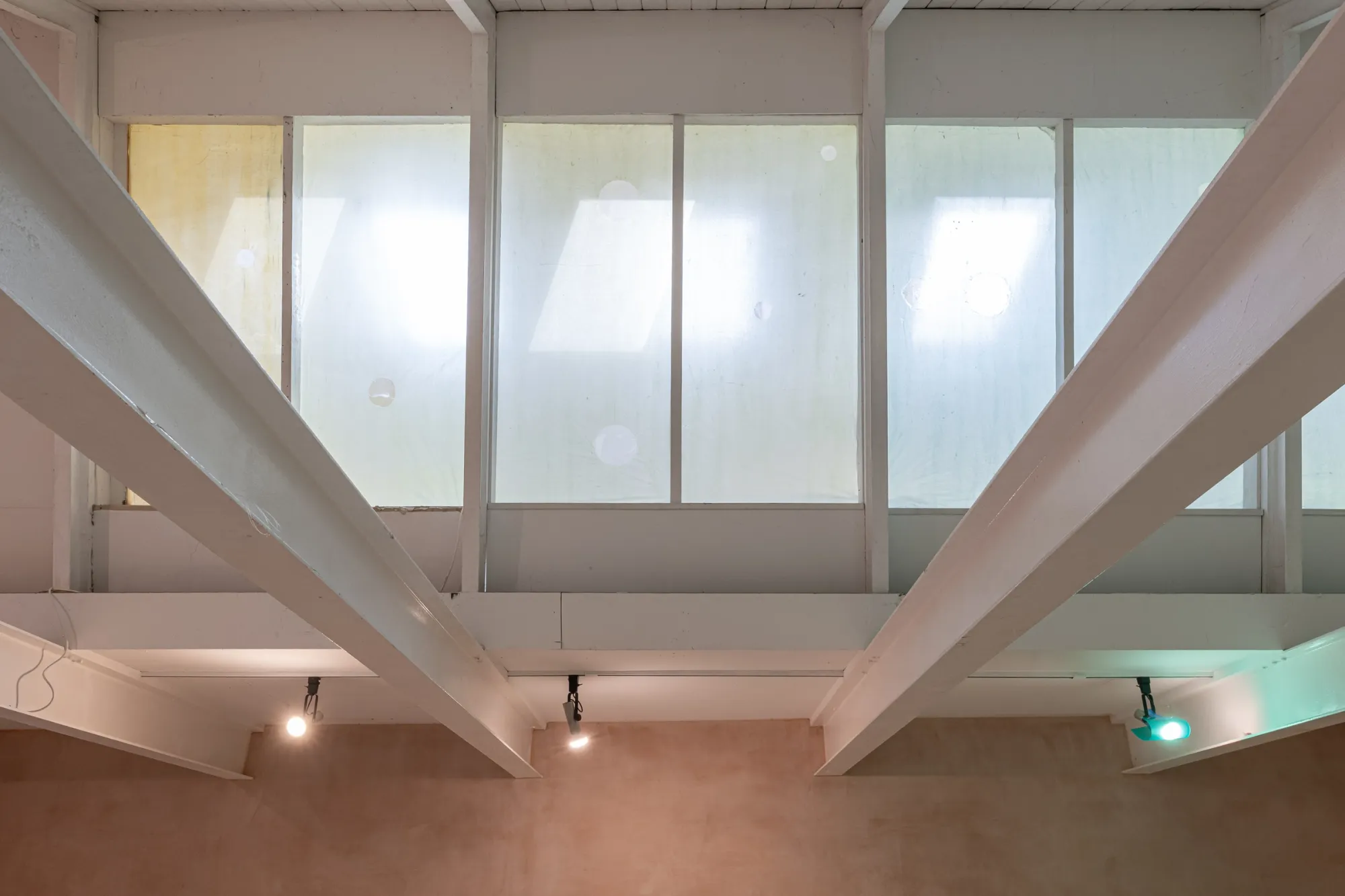 Gallery roof beams and upper windows covered with pale membranes and circular marks in Finbar Prior's The Mucous Vaults, OUTPOST Gallery, Norwich, 2026.