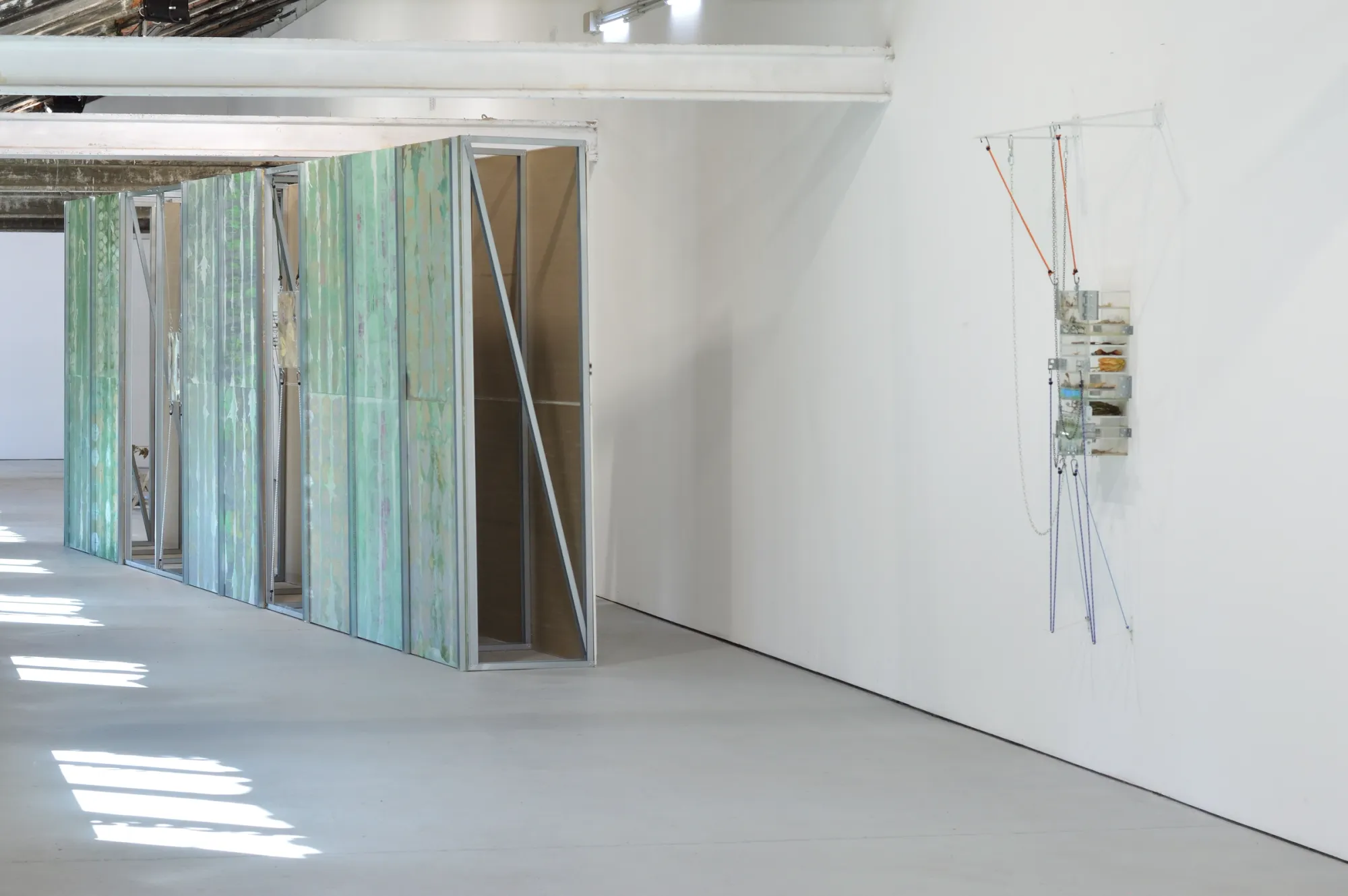 Exhibition review of Gabriel Alonso: A Long Chemical Dream at ATM Galería, Gijón, 2026. Green printed wall beside a wall-mounted acrylic box hung with cords.