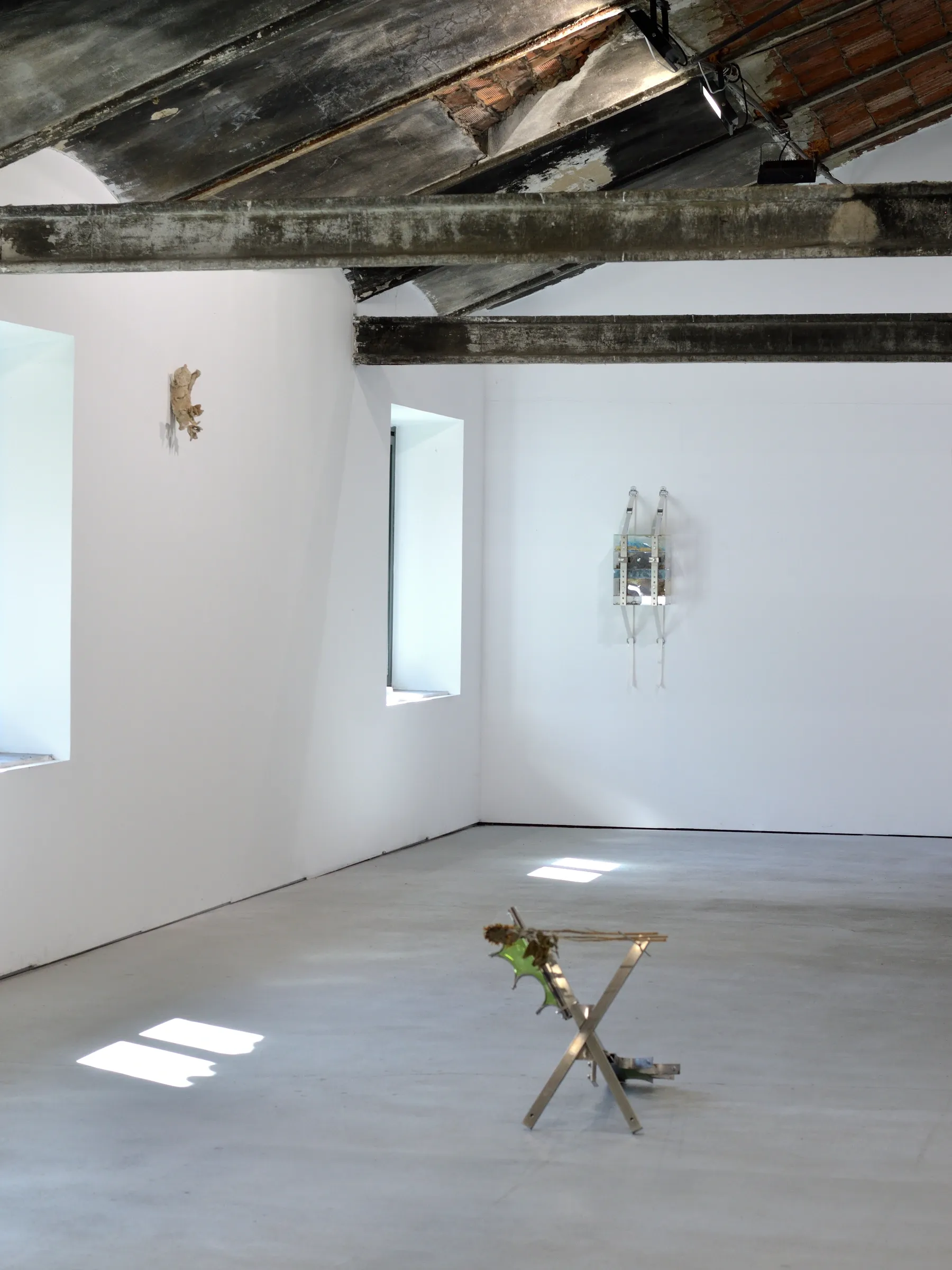 Exhibition review of Gabriel Alonso: A Long Chemical Dream at ATM Galería, Gijón, 2026. White room with timber beams, a steel X-frame on the floor, wall works.