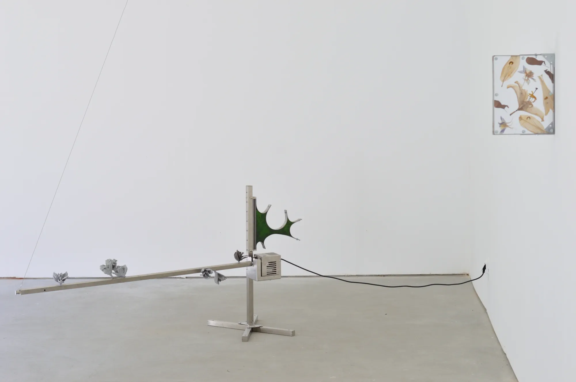Exhibition review of Gabriel Alonso: A Long Chemical Dream at ATM Galería, Gijón, 2026. Steel stand and lever on the floor, pressed-flower panel on the wall.