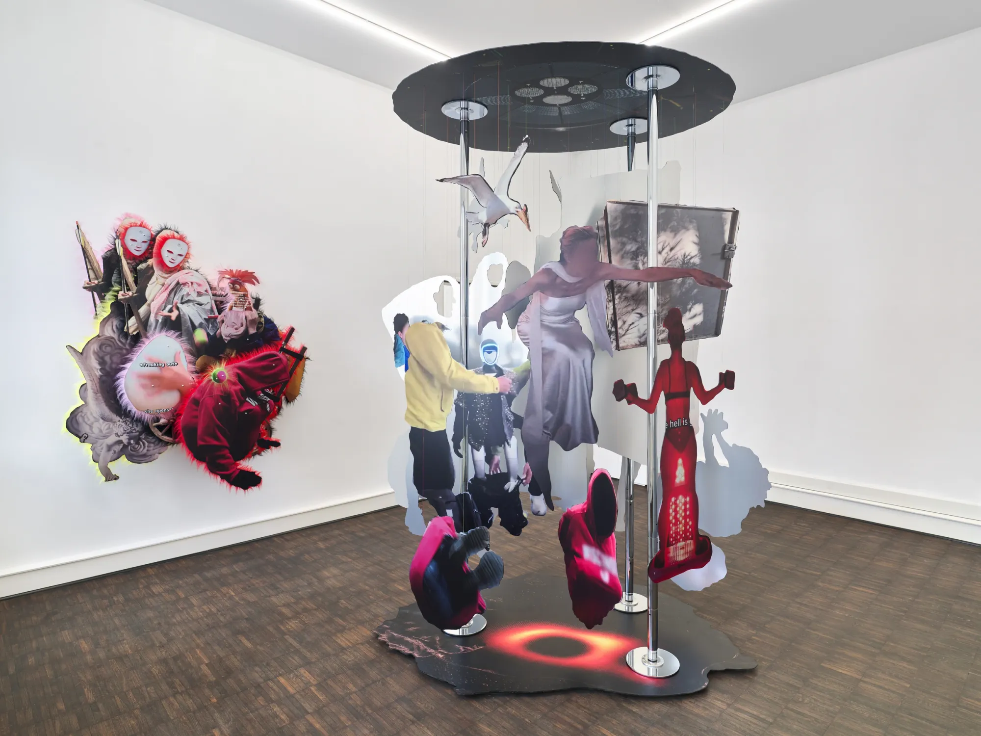 Exhibition review of Iris Helena Hamers: ~^-.3N3RGY_4NG3L.-^~ at PAW, Düsseldorf, 2026. Dance pole sculpture with printed figures and a seagull cut-out, beside a wall work of white-masked faces and red garment motifs.