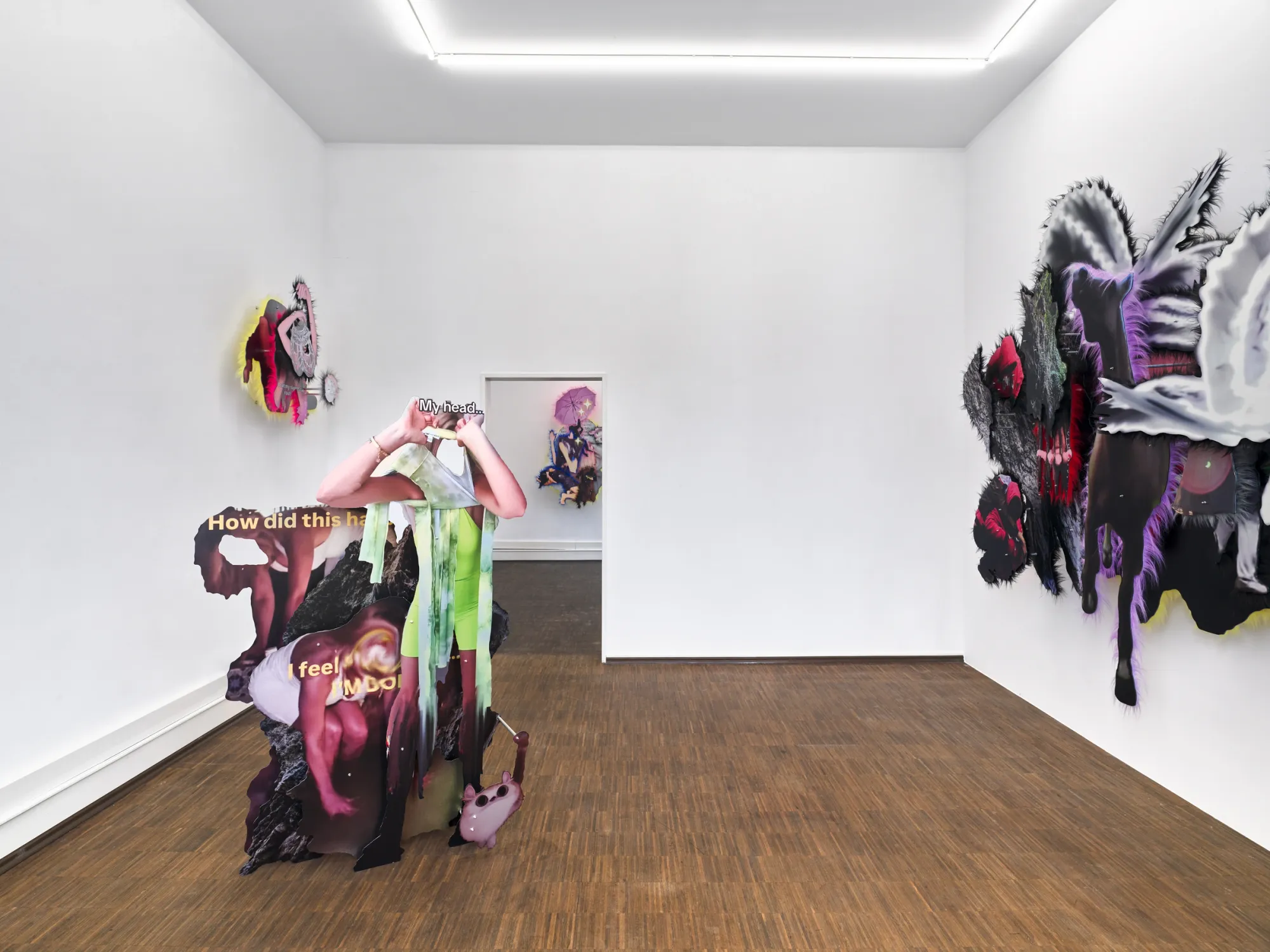 Exhibition review of Iris Helena Hamers: ~^-.3N3RGY_4NG3L.-^~ at PAW, Düsseldorf, 2026. Standing printed cut-out figure with green drips and yellow text, a fur-edged wall work at right and a doorway to another room.
