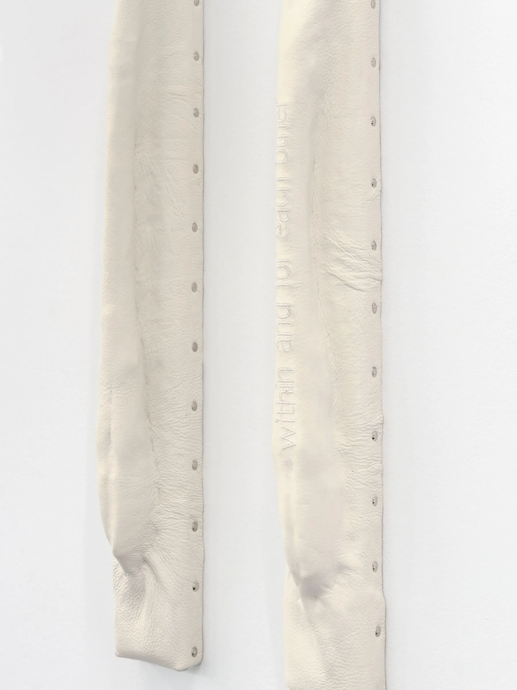 Close-up of two cream padded wall bars with rows of metal studs and faint lettering. Jan Baszak, Within and For Each Other, Warsaw, 2026.