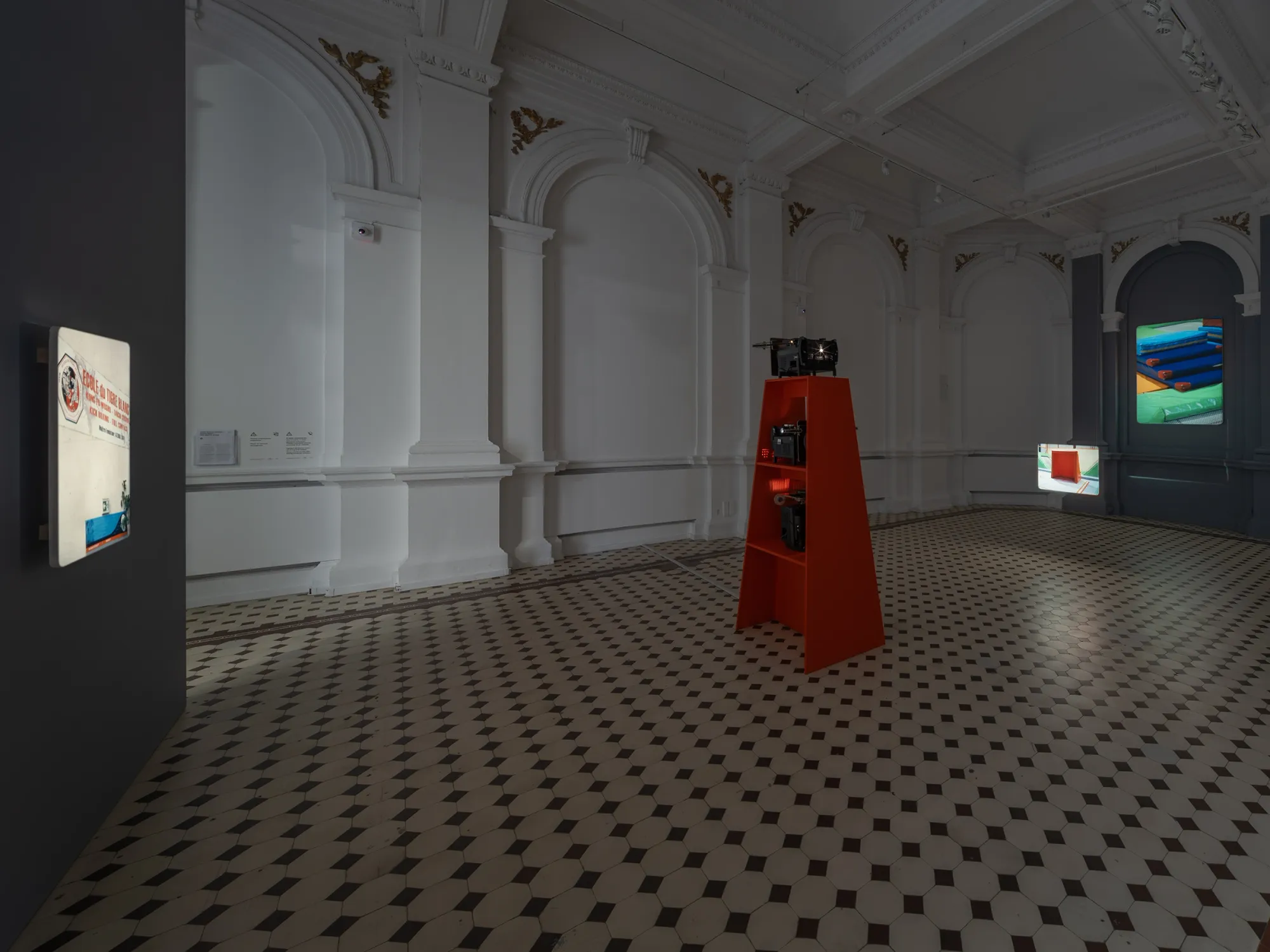 João Maria Gusmão, Zachęta, Warsaw: red projector stand in a tiled hall facing a lit wall projection.