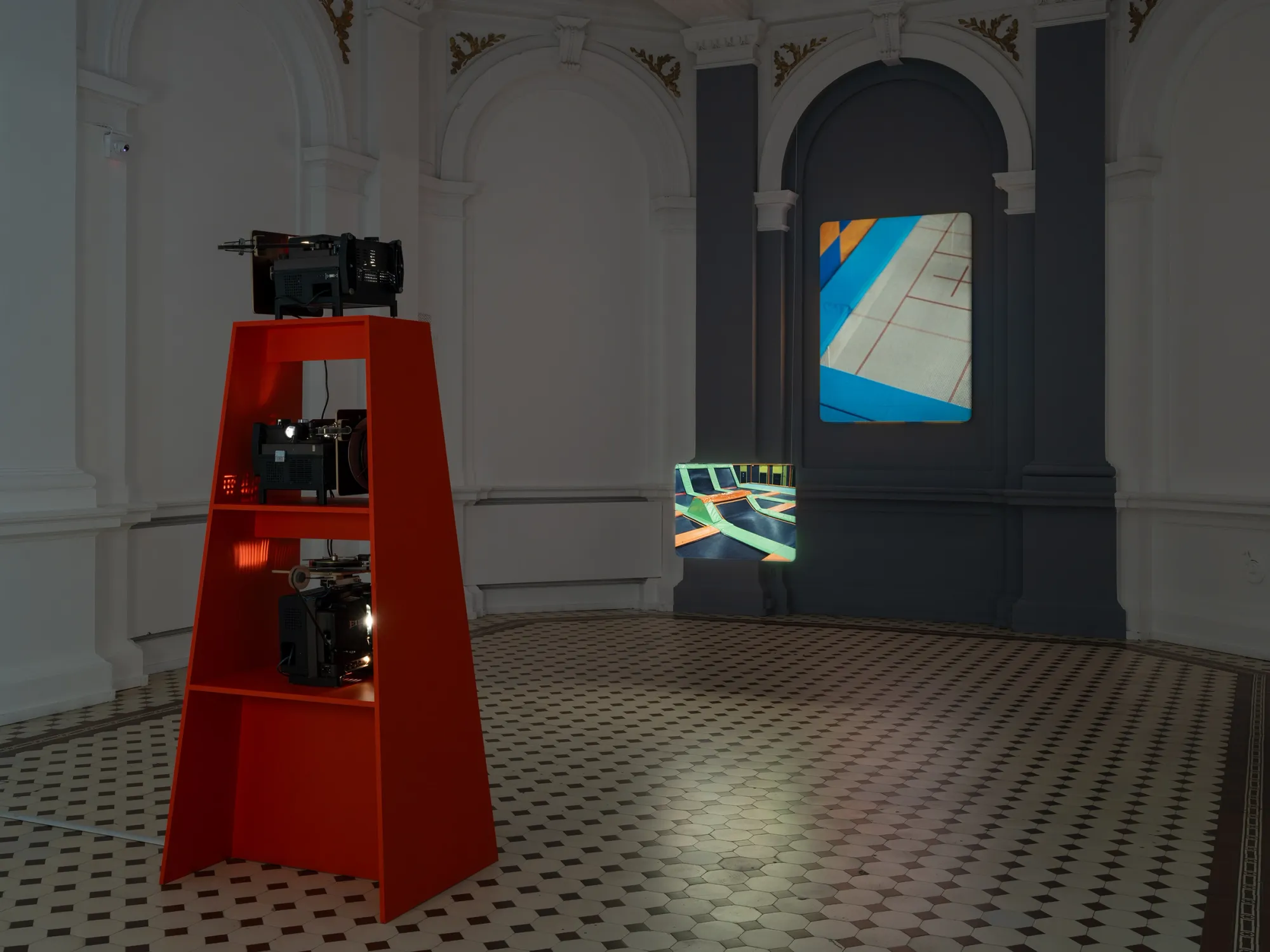 João Maria Gusmão, Zachęta, Warsaw: red projector stand facing a vertical blue and orange projection and a small trampoline image.