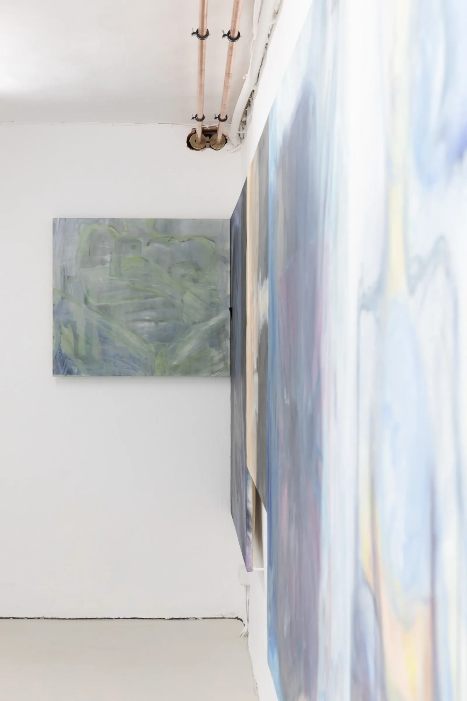 Exhibition review of Krys Huba: falling into you at soft power, Berlin, 2026. Green painting on the end wall seen past a blurred canvas edge.