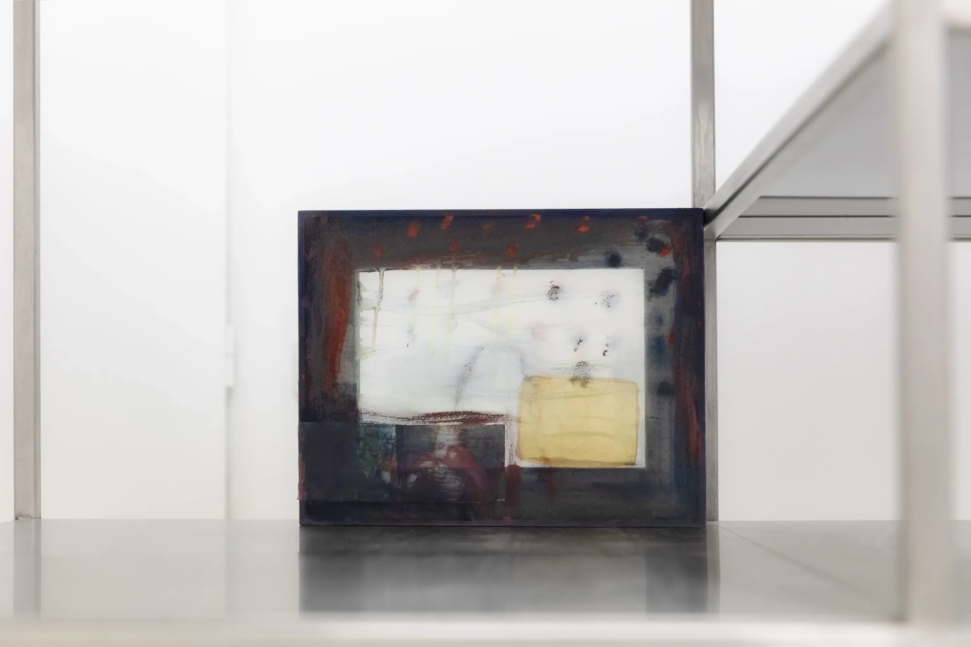 Exhibition review of Krys Huba: falling into you at soft power, Berlin, 2026. Small dark framed work on transparent fabric standing on a steel shelf.