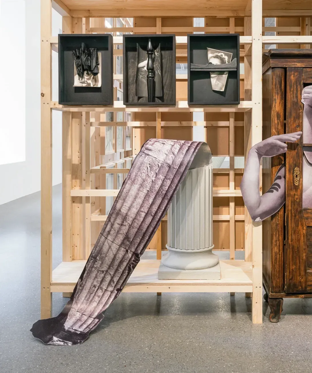 Lucia Tallová, PalaisPopulaire, Berlin: purple-toned paper strip trailing from a fluted column beside a printed arm and a cabinet.