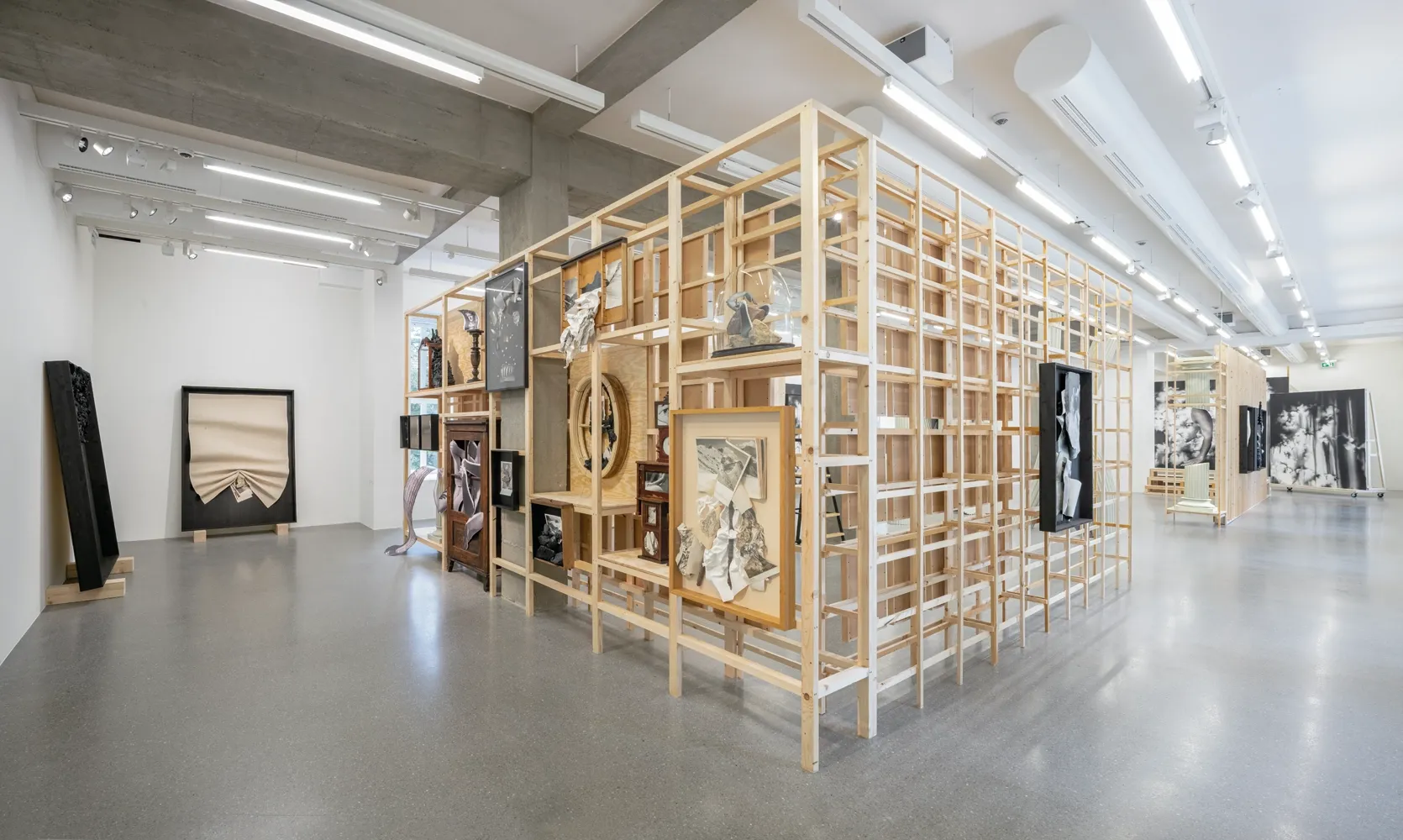 Lucia Tallová, PalaisPopulaire, Berlin: long gallery room with a wooden lattice structure and framed works along the walls.