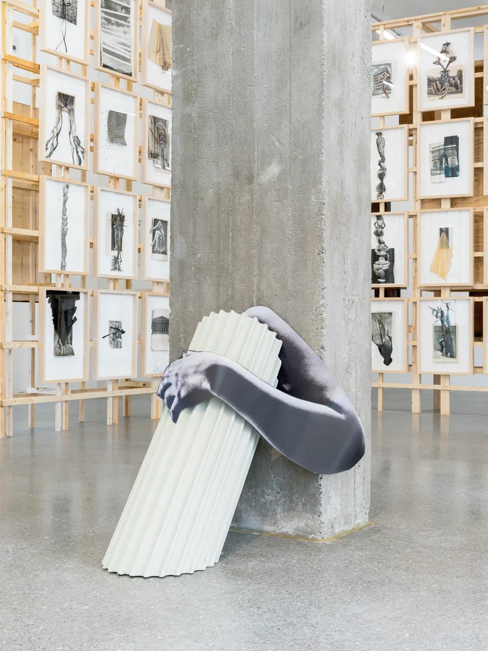 Lucia Tallová, PalaisPopulaire, Berlin: printed grey arm wrapped around a pale fluted column leaning on a concrete pillar.