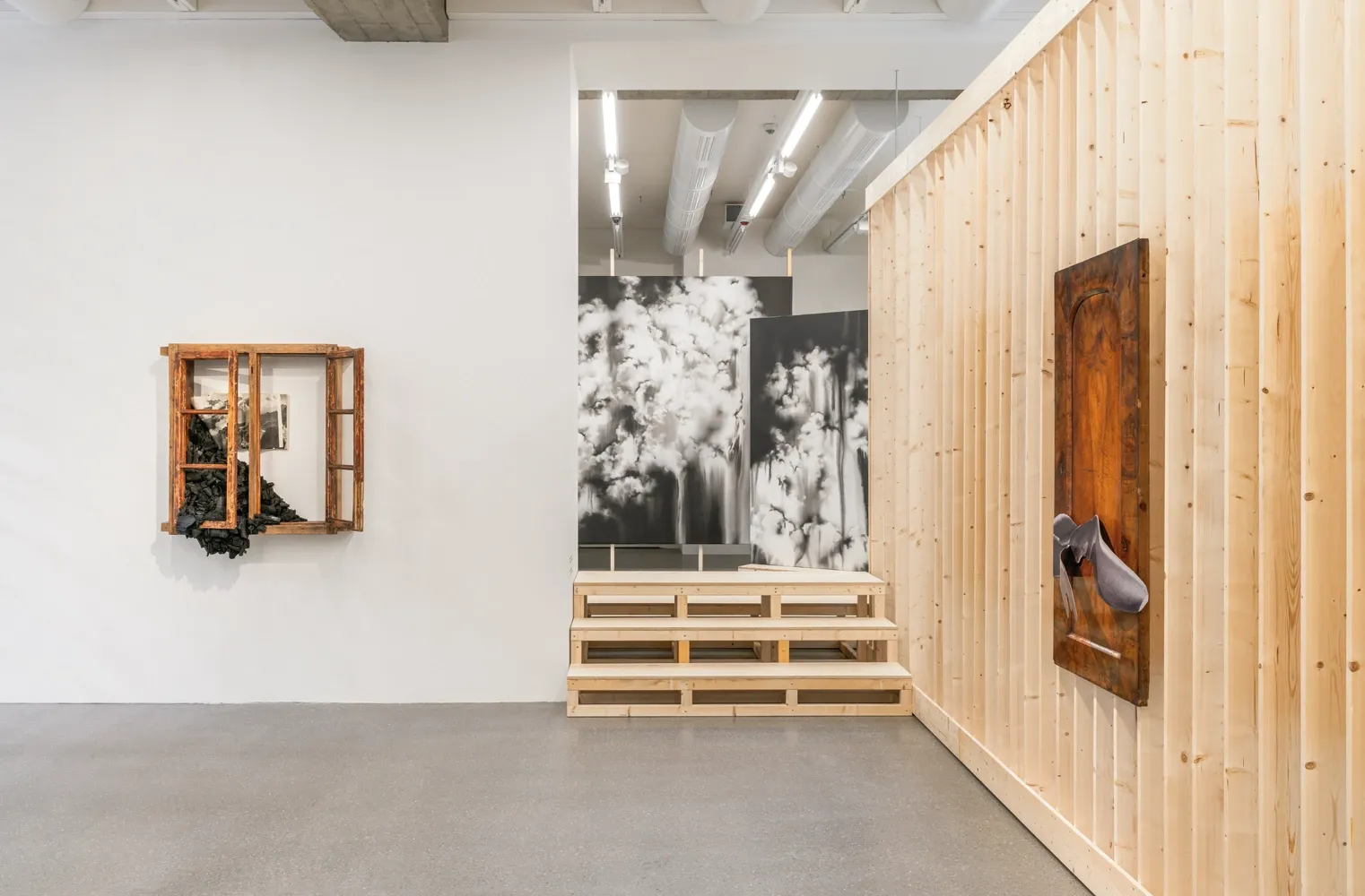 Lucia Tallová, PalaisPopulaire, Berlin: window frame filled with charcoal, cloud paintings behind timber steps and a slatted timber wall.