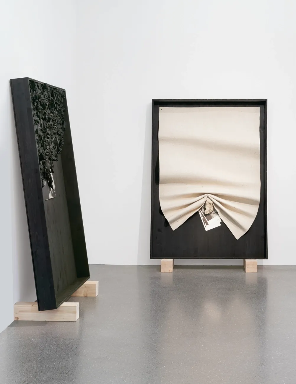 Lucia Tallová, PalaisPopulaire, Berlin: two black-framed works, one topped with charcoal pieces, one with gathered cream-coloured fabric