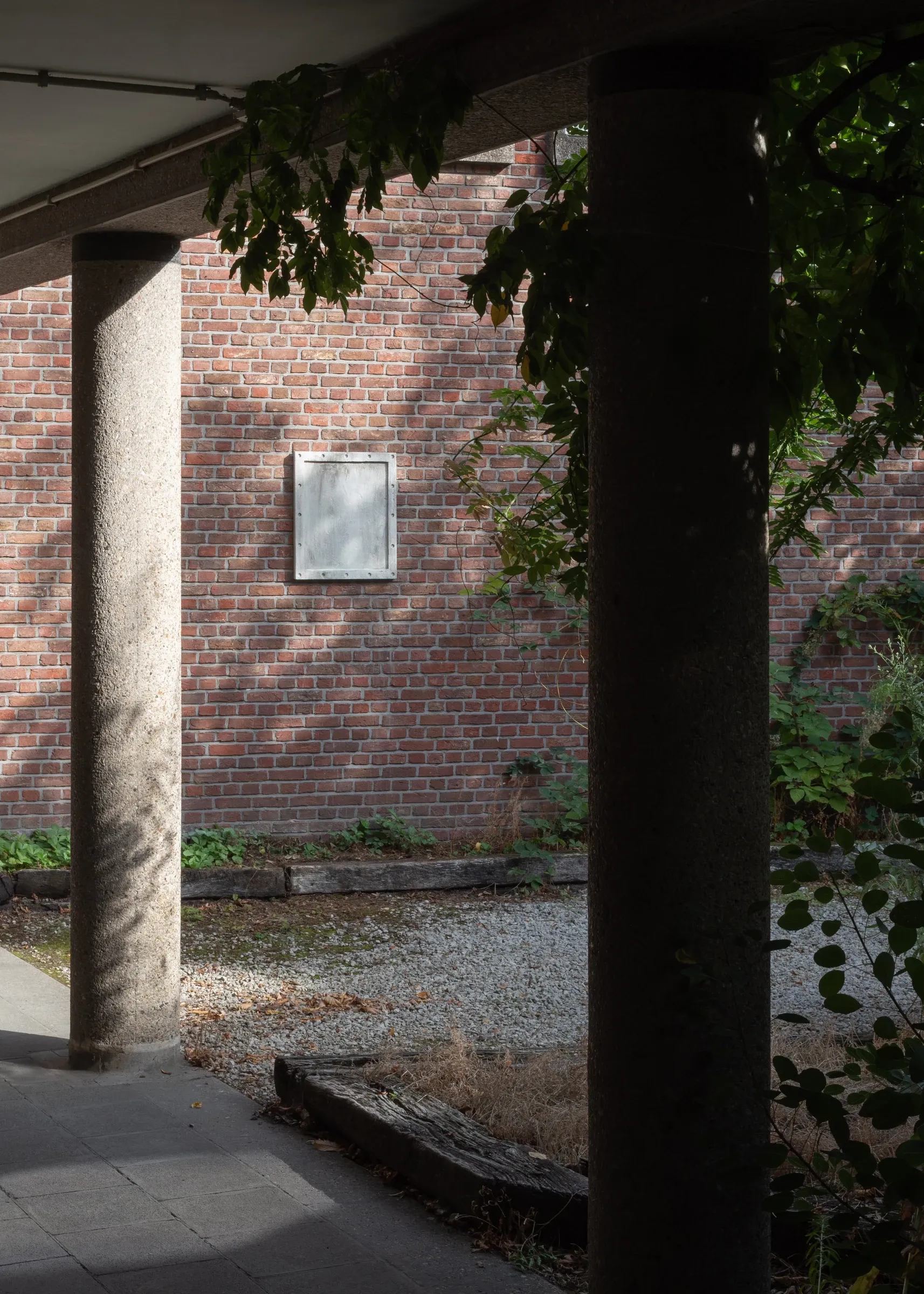 Exhibition review of Simon Bultynck: A. Aubry, A. Colin, P. Lippens, A. Oosterlinck, C. Wynants at CONVENT Space for Contemporary Art, Ghent, 2026. Pale concrete panel with a recessed field and bolt holes on a red brick wall, framed by two concrete columns.