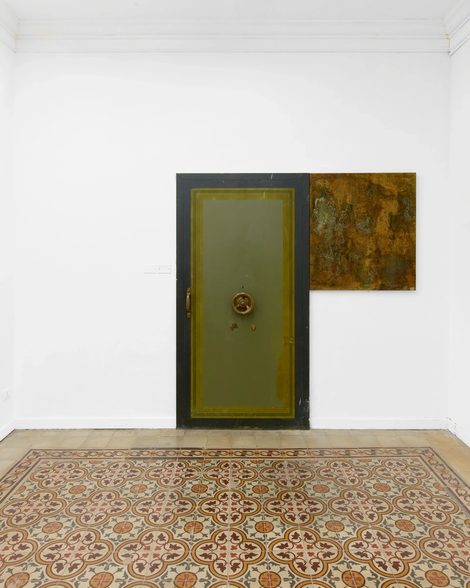 Taylah Hasaballah, INDICATRIX at The Address, Brescia, 2026. Olive-green door beside a rust-orange painting on a white wall.