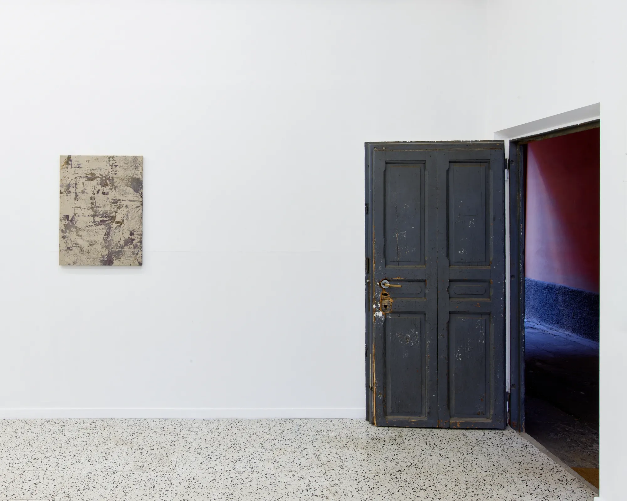 Taylah Hasaballah, INDICATRIX at The Address, Milan, 2026. Small beige-violet painting beside an open dark door with red interior.