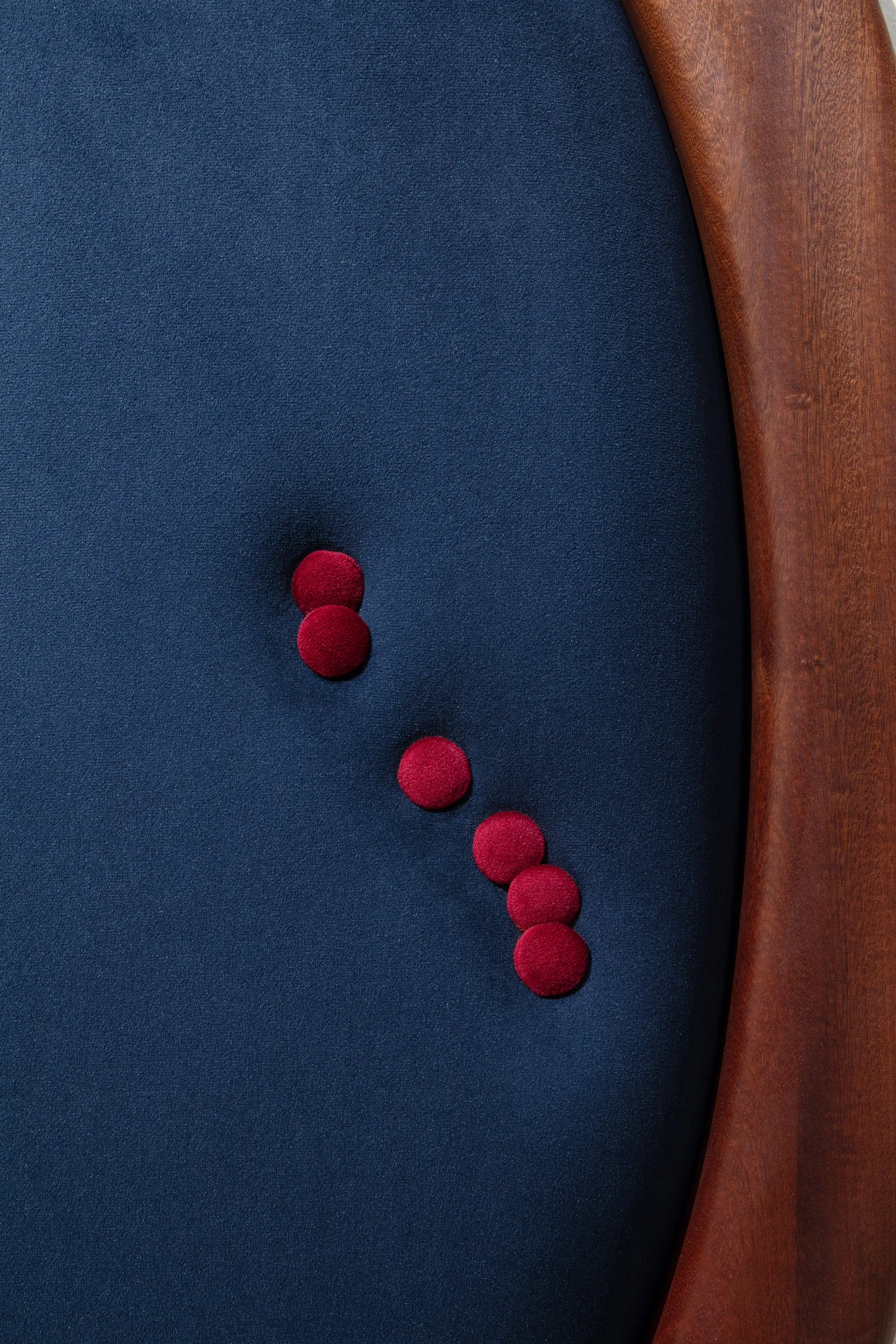 Tereza Kalousová, Clauda, Prague: close-up of red velvet buttons on navy velvet beside a wooden frame.