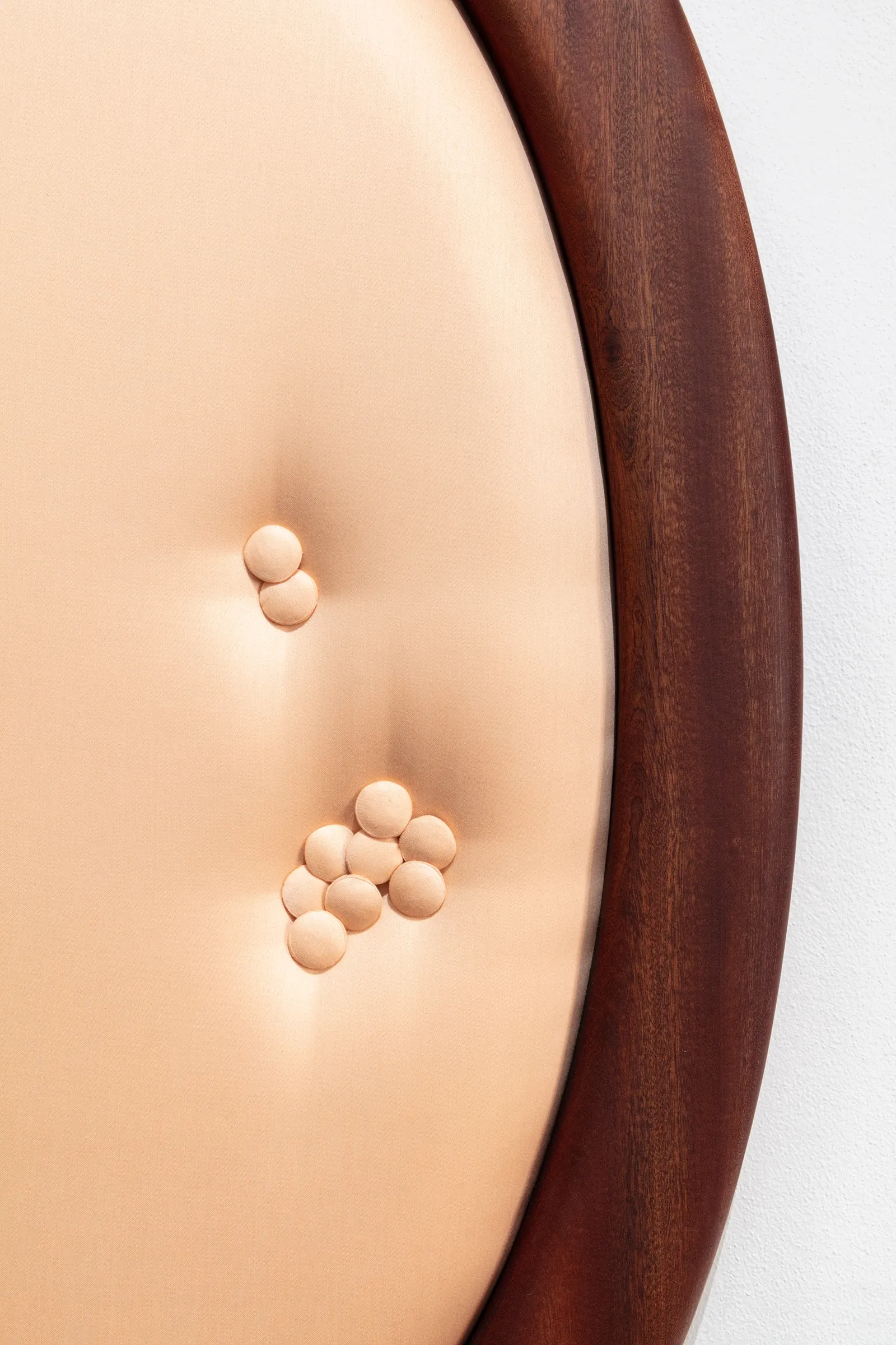 ALT: Tereza Kalousová, Clauda, Prague: close-up of peach buttons clustered on peach upholstery beside a wooden frame.