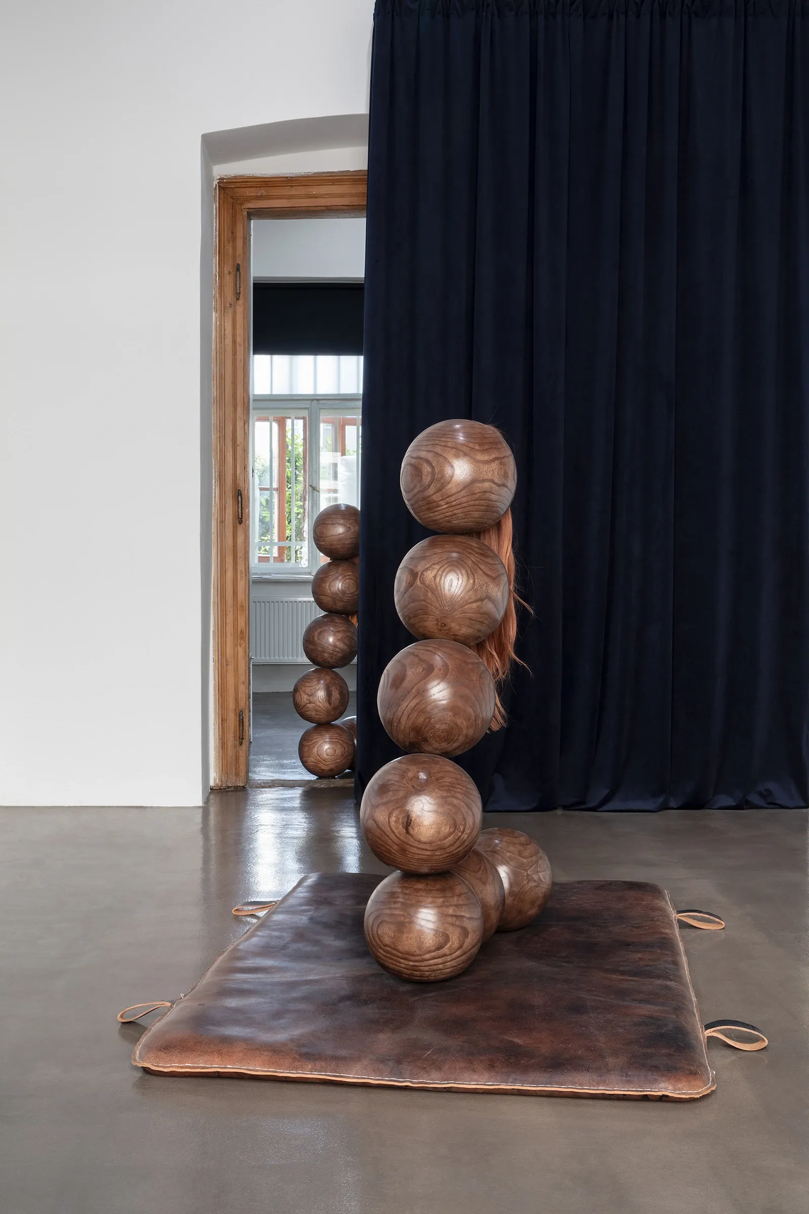 Tereza Kalousová, Clauda, Prague: wooden sphere column with synthetic hair on a leather mat in front of a navy velvet curtain.