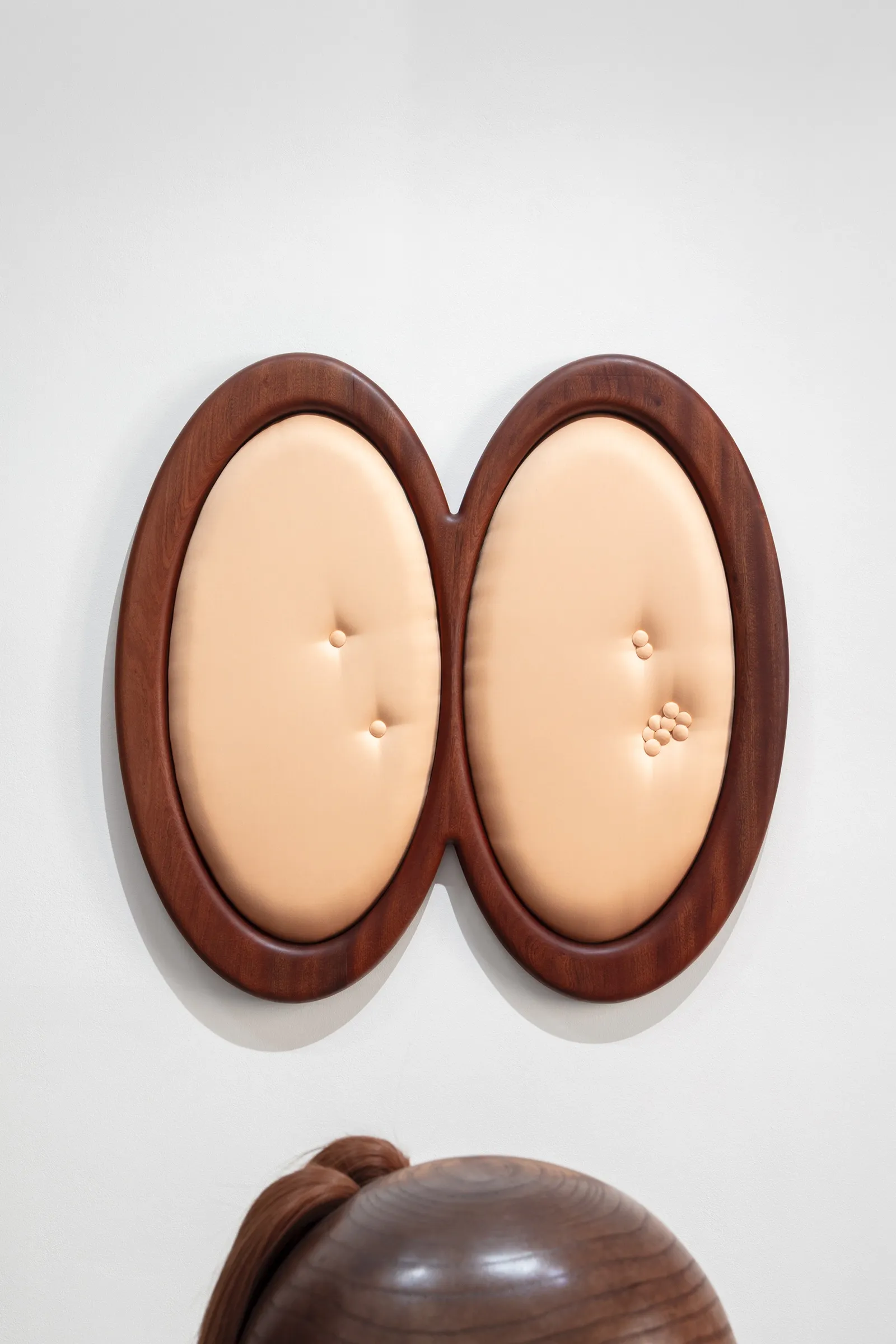 Tereza Kalousová, Clauda, Prague: double-oval wooden frame with peach upholstery and clustered buttons.