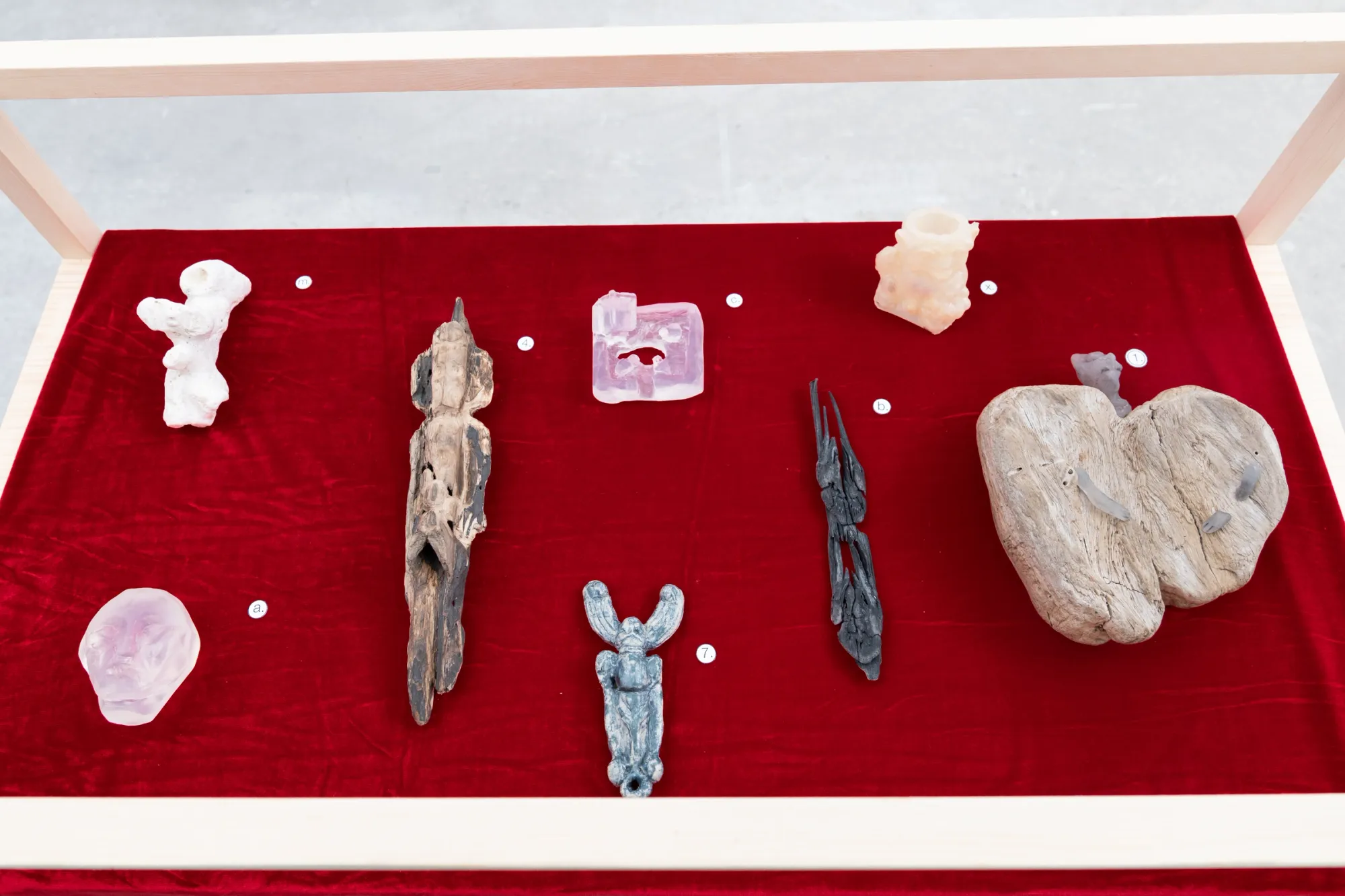 Yasy Bachurina, Studiya, Seoul: Driftwood, pale resin and carved fragments laid on red velvet inside a wooden vitrine.